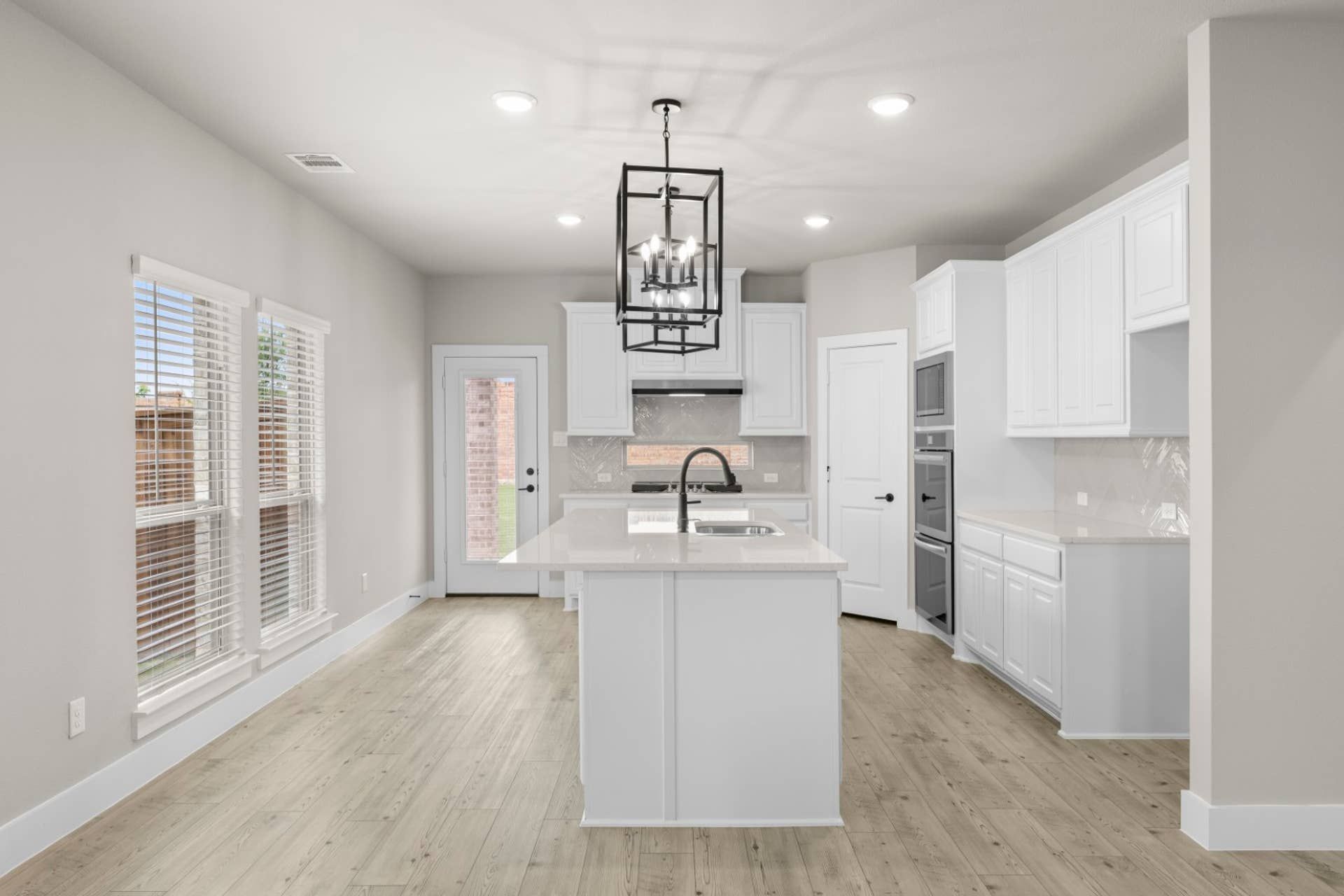 Modern kitchen with white cabinetry, island, and pendant lighting.