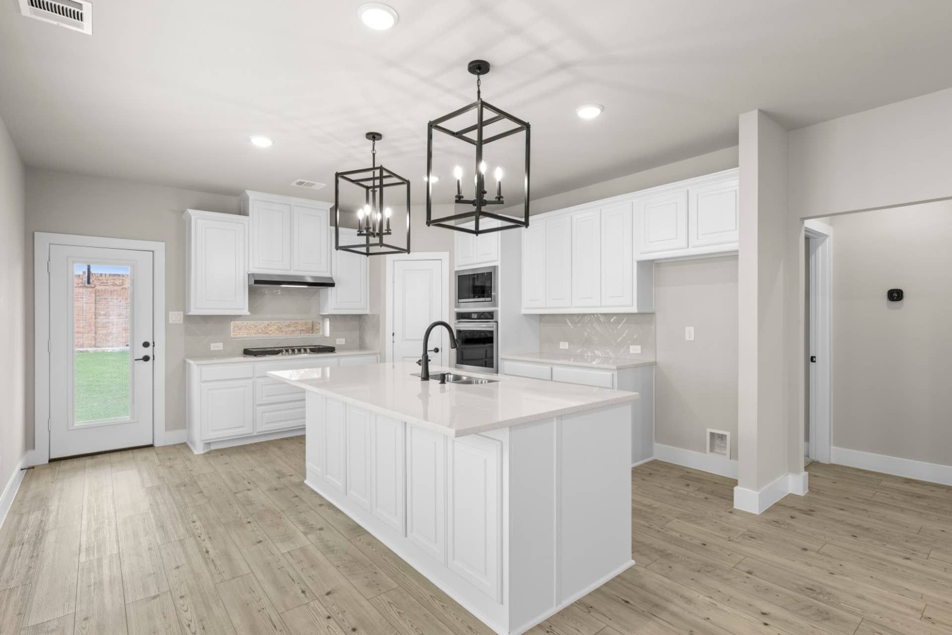 Modern kitchen with white cabinetry, island, and pendant lighting.