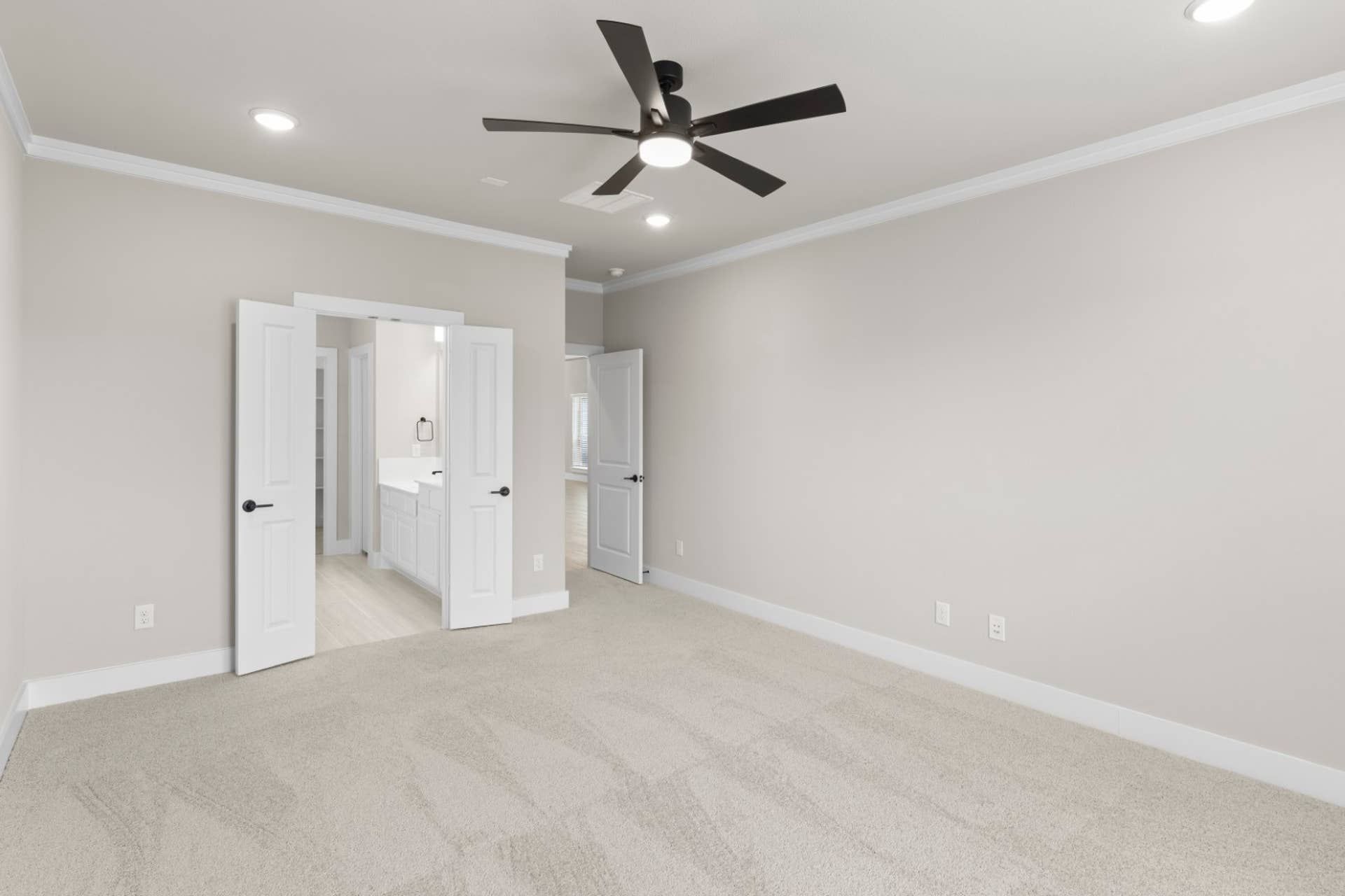Spacious bedroom with ceiling fan and double doors leading to ensuite bathroom.