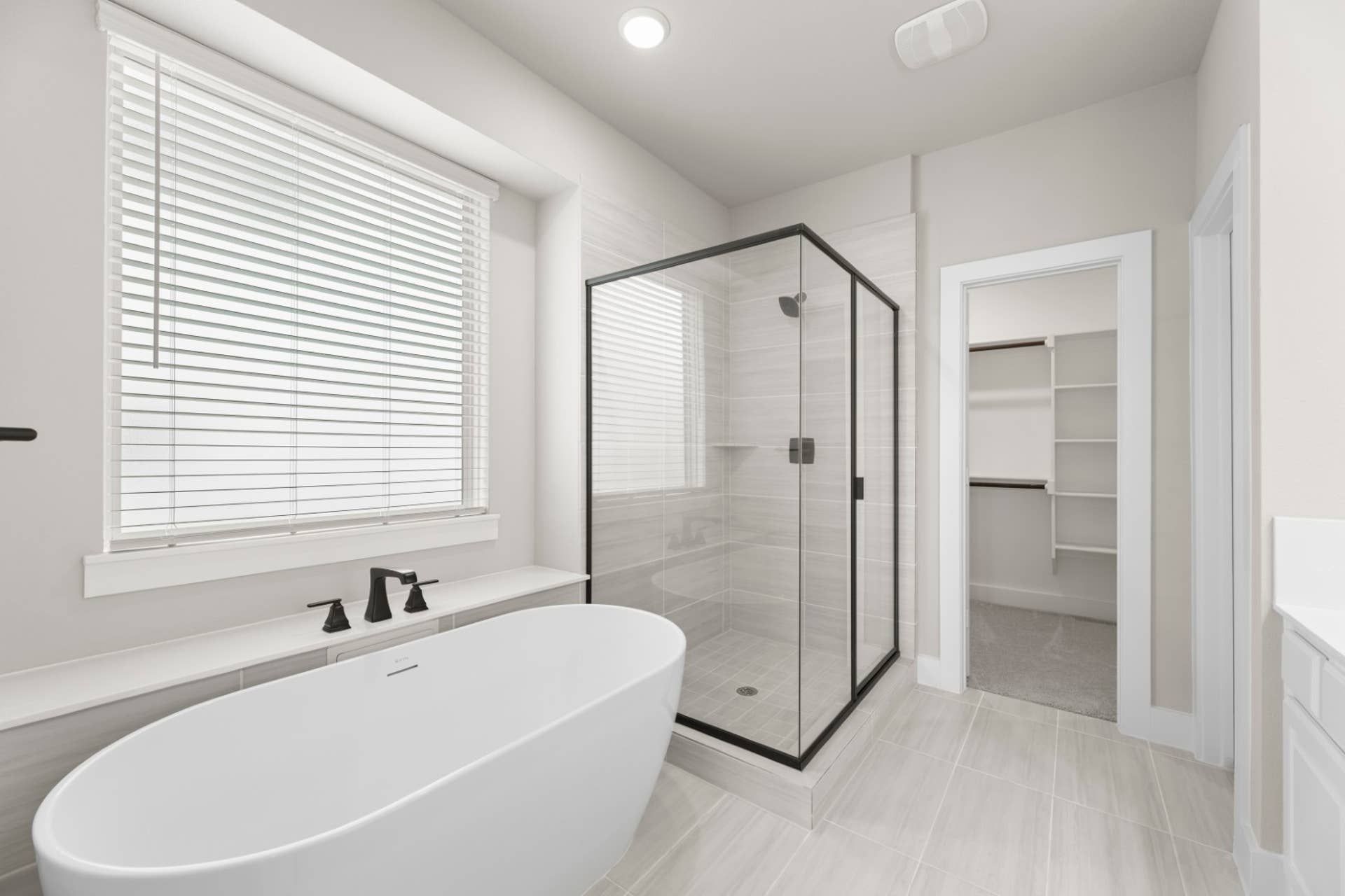 Modern bathroom with freestanding tub, glass shower, and walk-in closet.