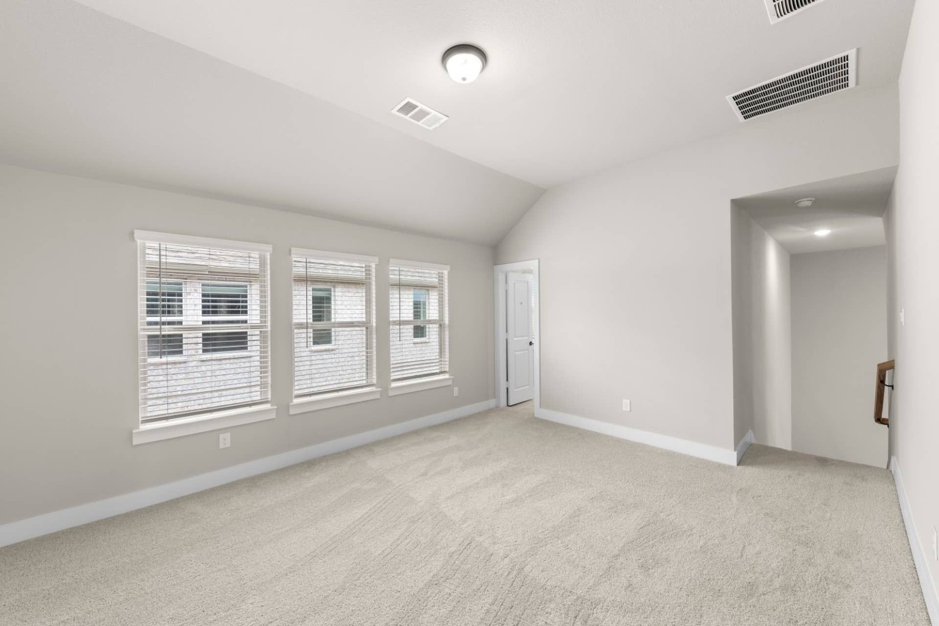 Spacious interior room with carpeted floor and large windows.