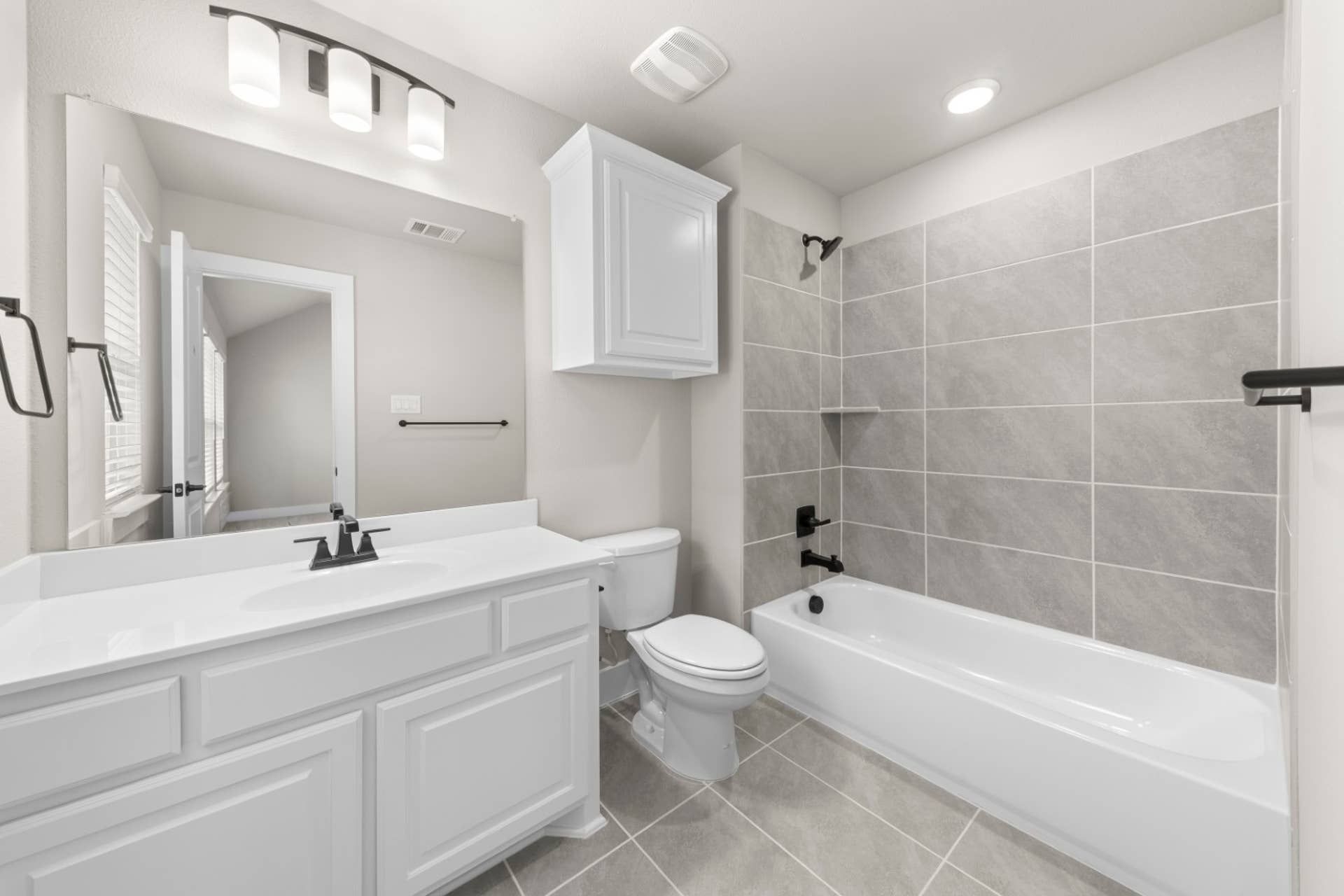 Modern bathroom with white vanity, tiled shower, and sleek fixtures.