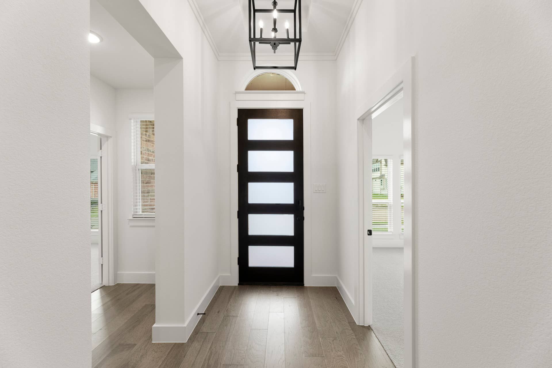 Contemporary entryway with frosted glass door and sleek hanging light fixture.