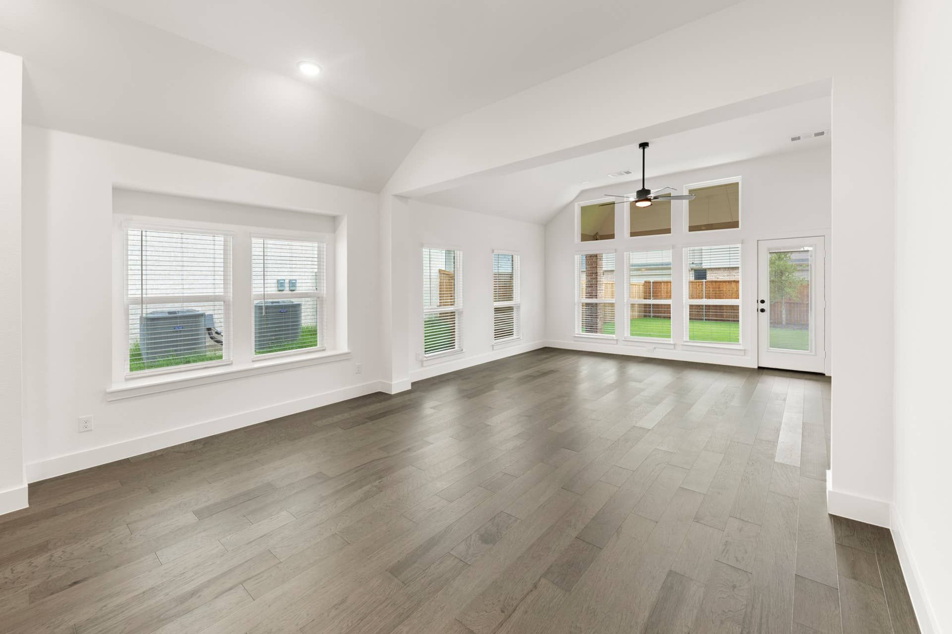 Spacious dining area with hardwood floors, large windows, and backyard view.