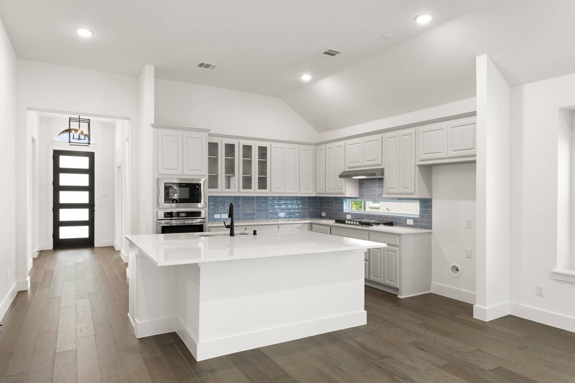 Modern kitchen with white cabinetry, island, and blue tile backsplash.