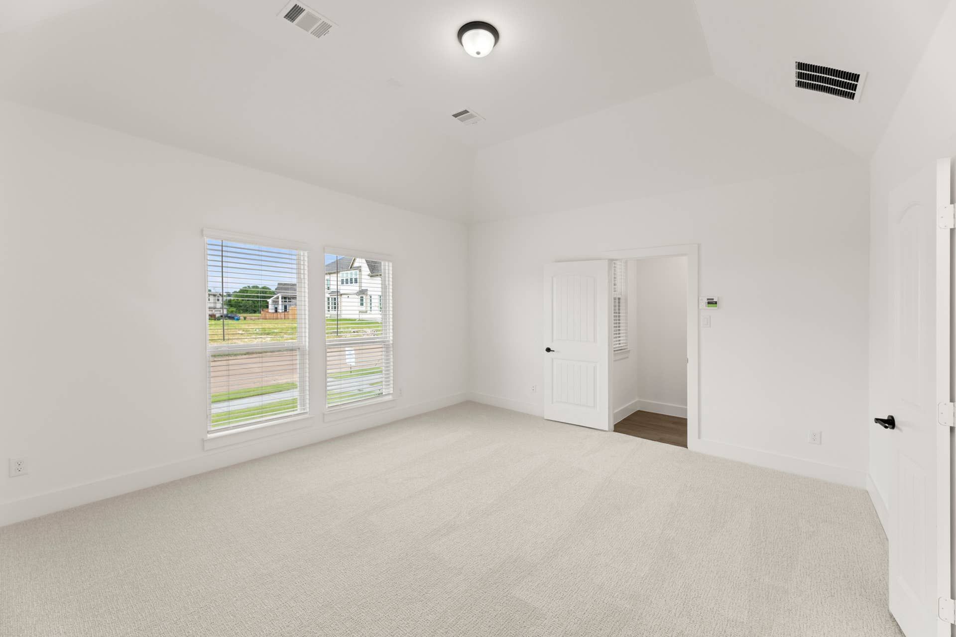 Spacious, carpeted room with large windows and a vaulted ceiling.