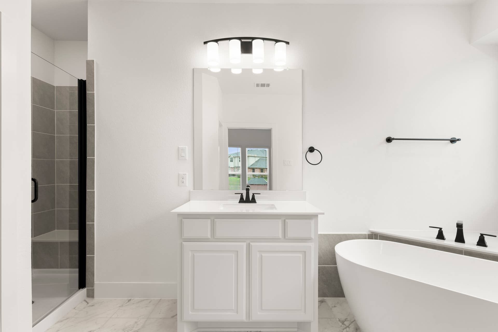 Modern bathroom with freestanding tub, glass shower, and elegant vanity lighting.