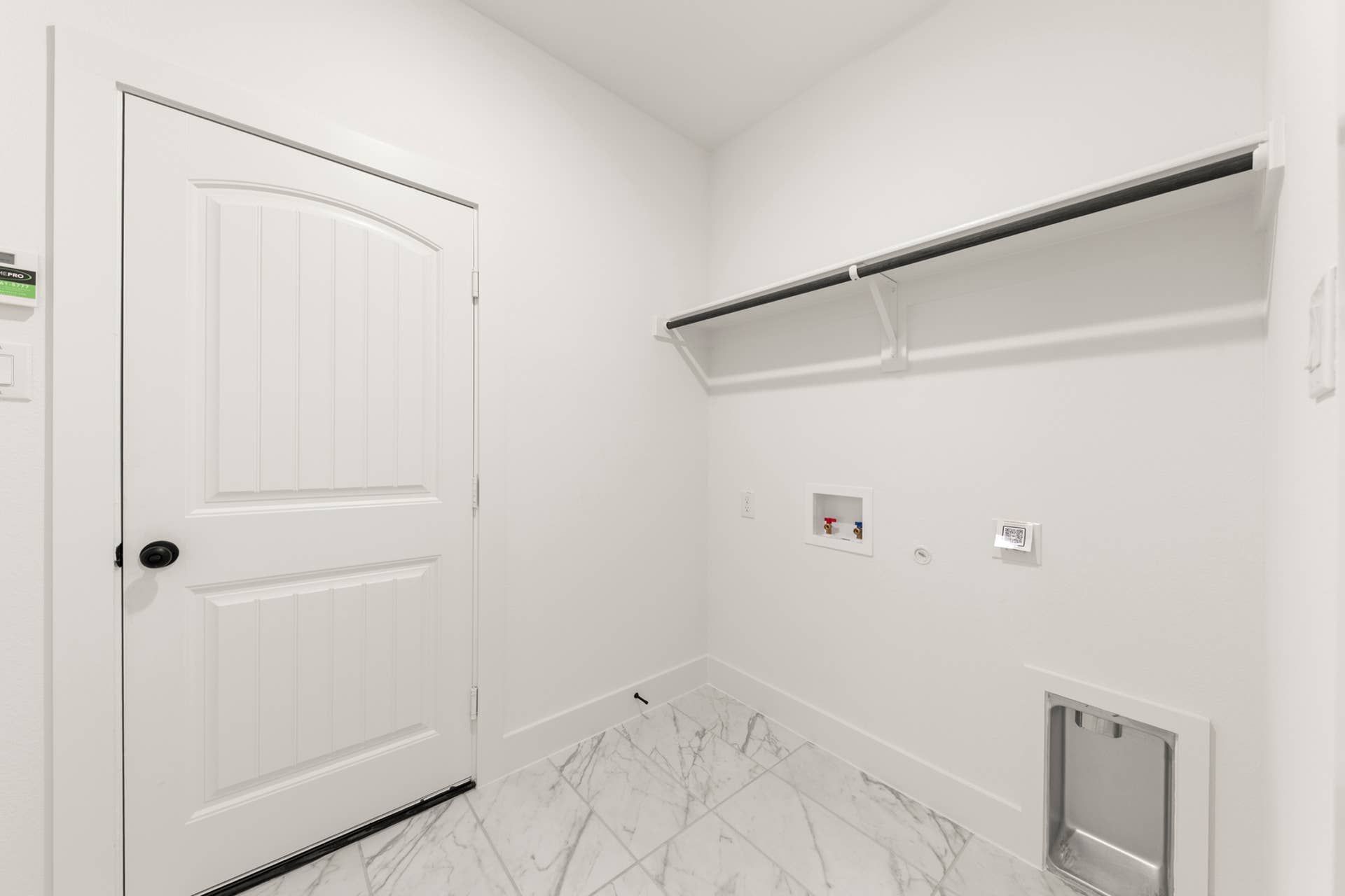 Spacious utility room with white door and marble tile flooring.