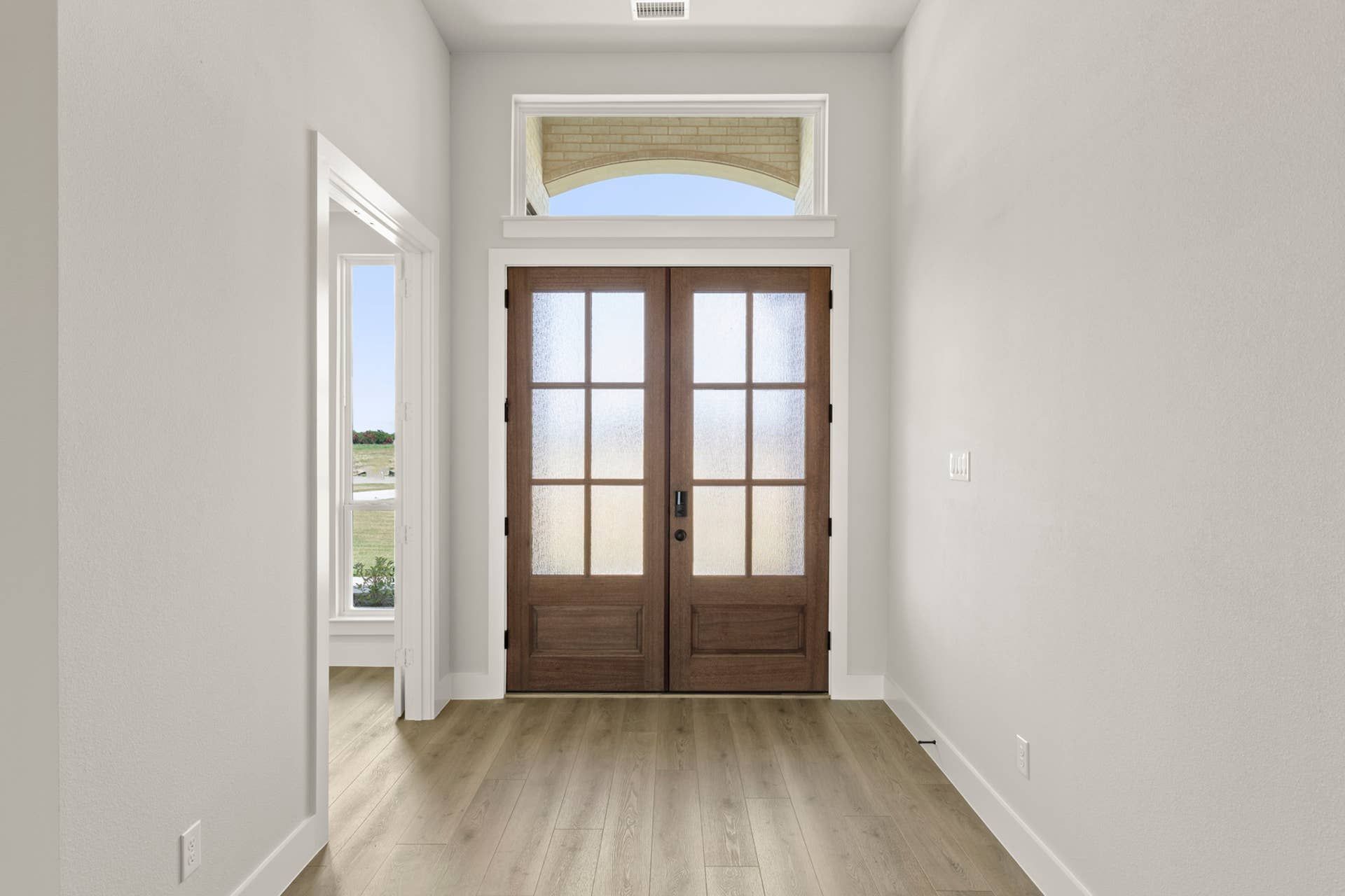 Spacious entryway with wooden double doors and transom window.
