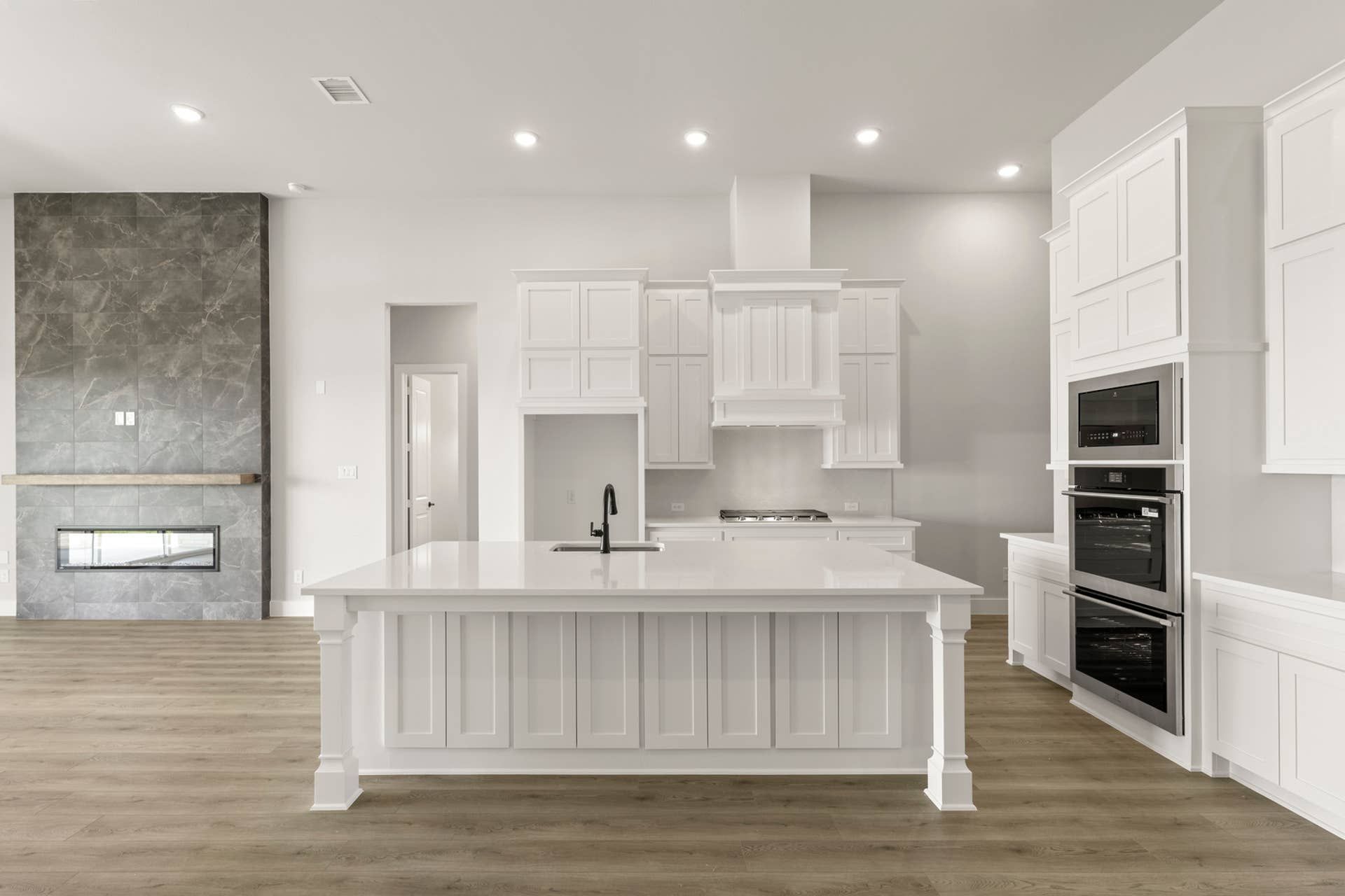Modern kitchen with white cabinetry, island, and built-in appliances.