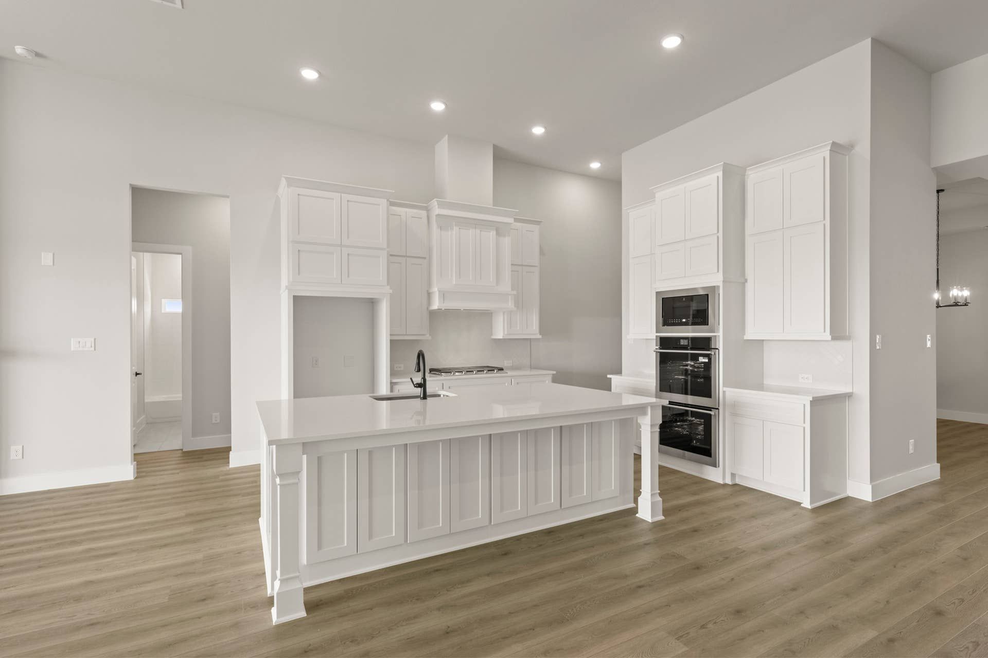Modern kitchen with white cabinetry, large island, and wood flooring.