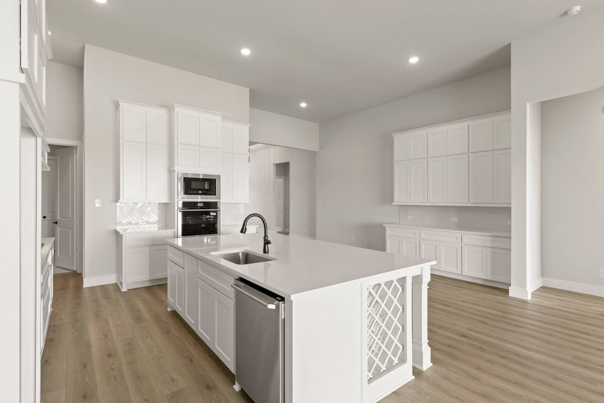 Modern kitchen with white cabinetry, island, and stainless steel appliances.