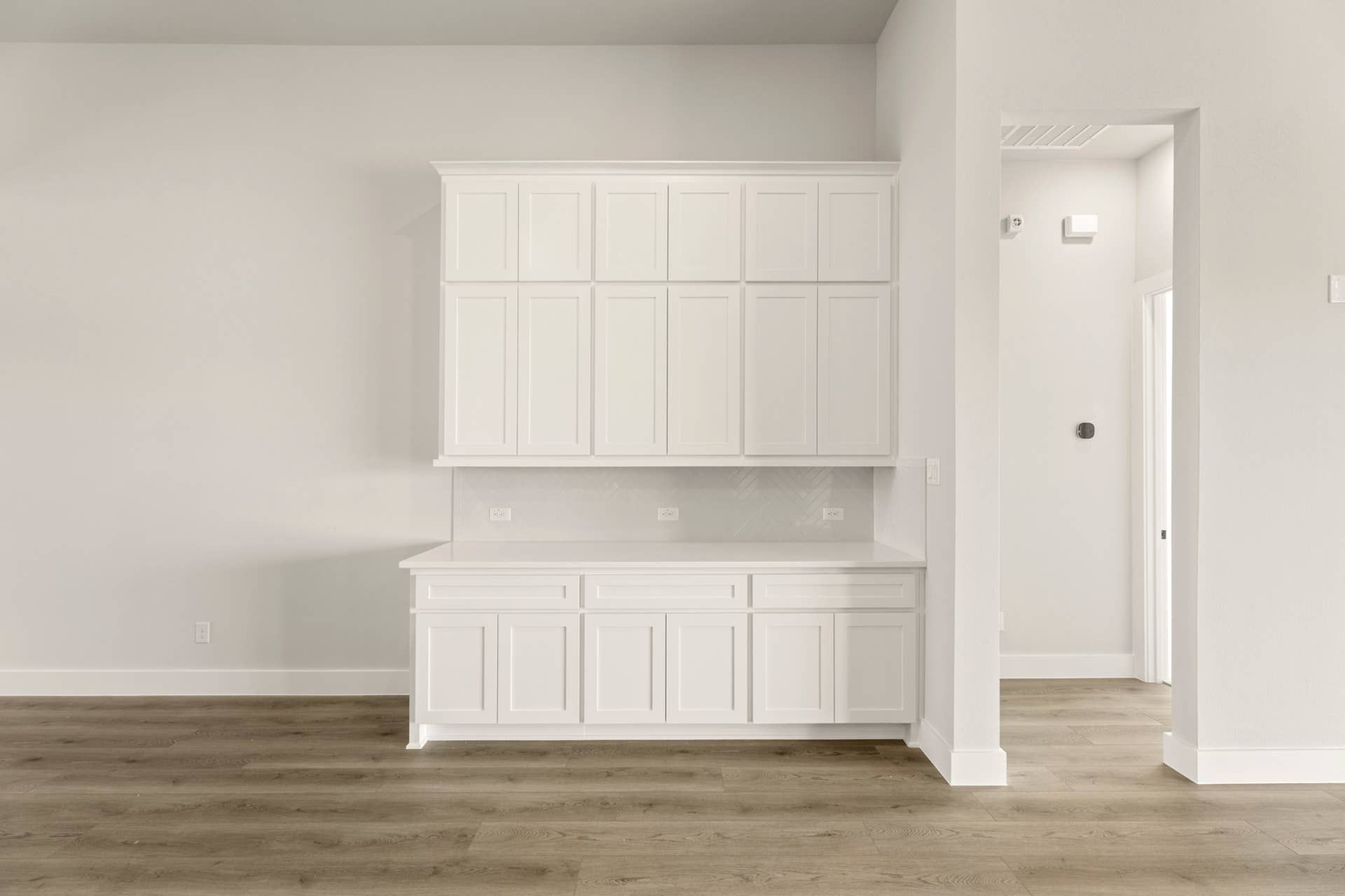 Spacious nook with white cabinetry and hardwood flooring.