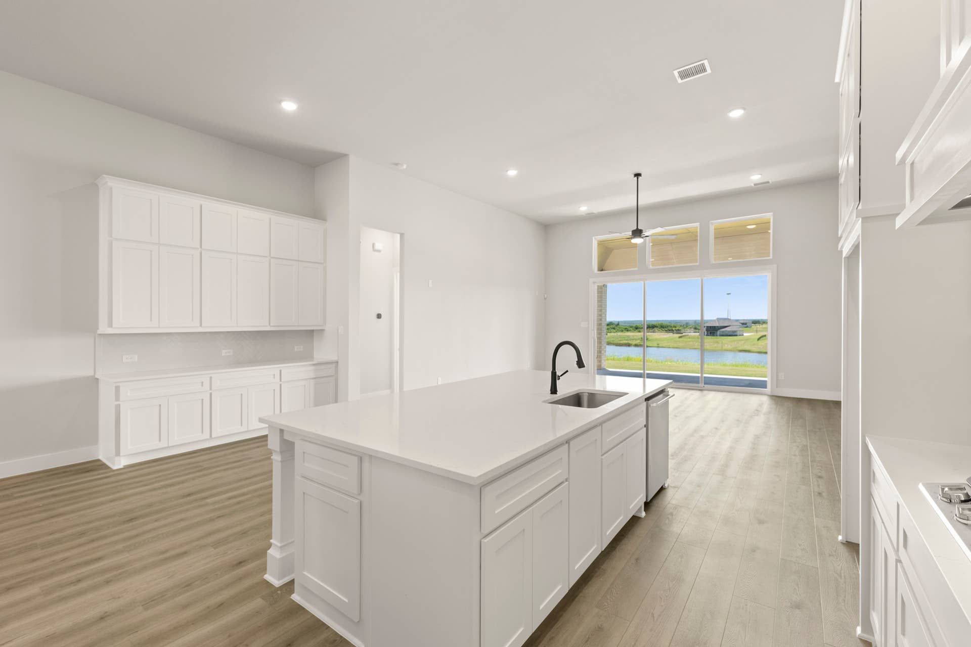 Spacious kitchen with white cabinetry, large island, and scenic outdoor view.