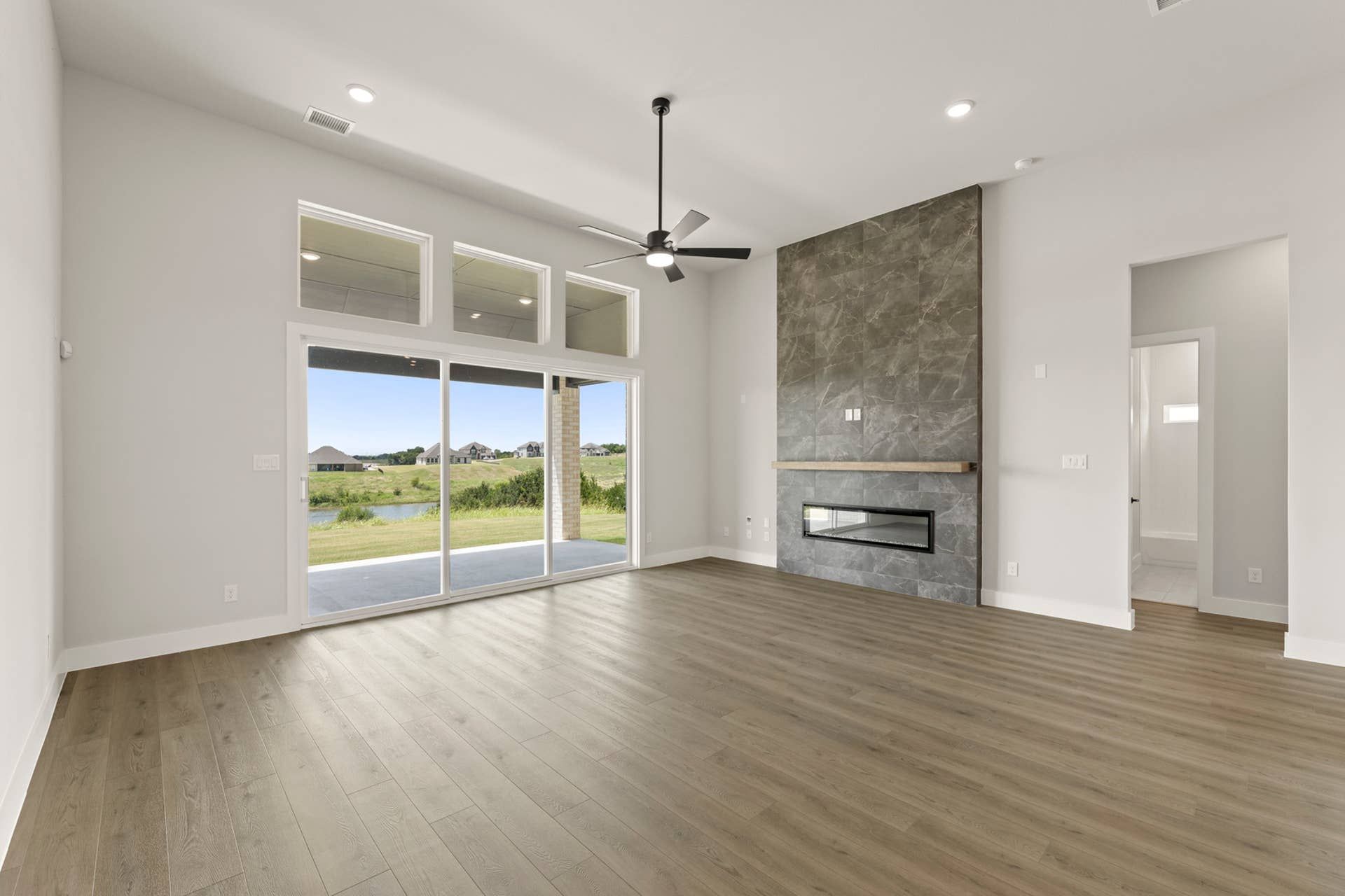 Spacious living room with modern fireplace and large windows overlooking backyard.