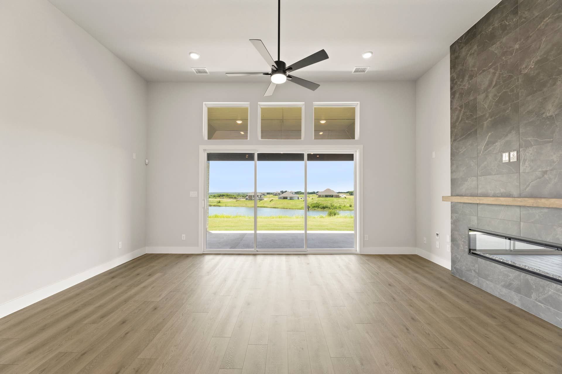 Spacious living room with large windows and modern fireplace overlooking a scenic lake view.