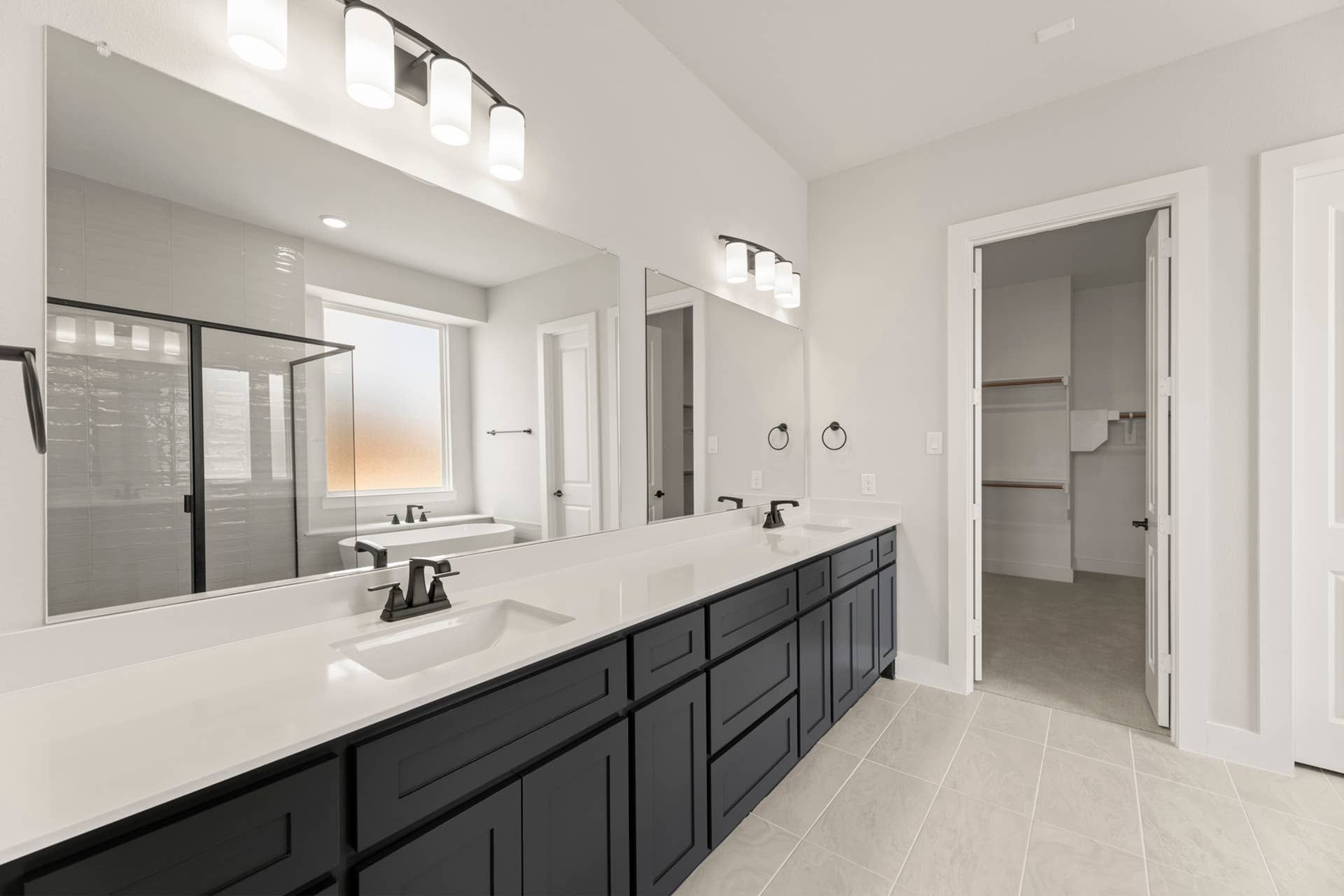 Spacious modern bathroom with dual sinks, large mirrors, and glass shower enclosure.