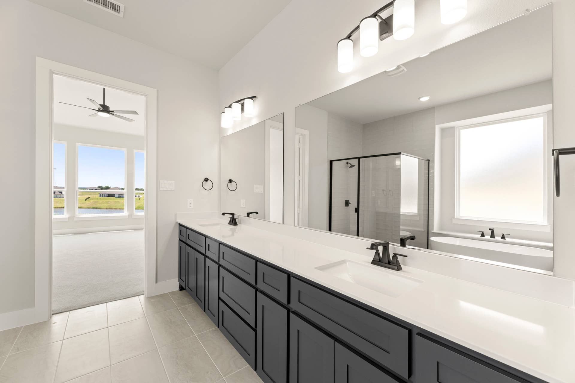 Modern bathroom with dual sinks, large mirror, and glass-enclosed shower.