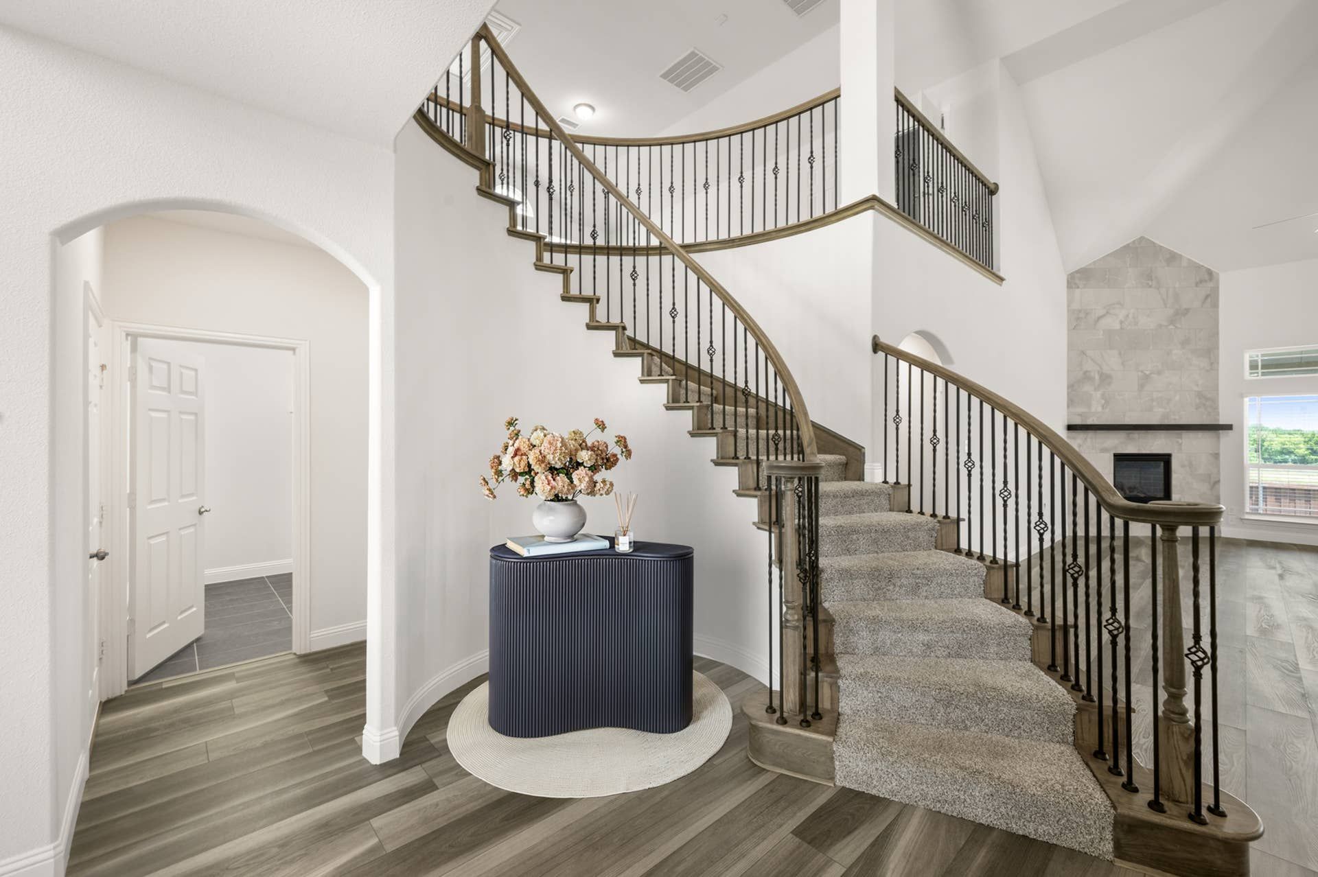 Elegant curved staircase with iron balusters in a modern entryway.