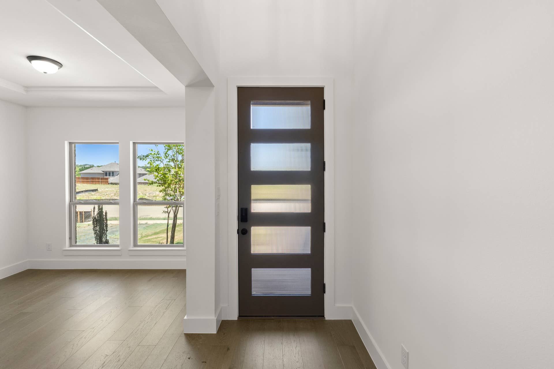 Modern entryway with frosted glass door and hardwood flooring.