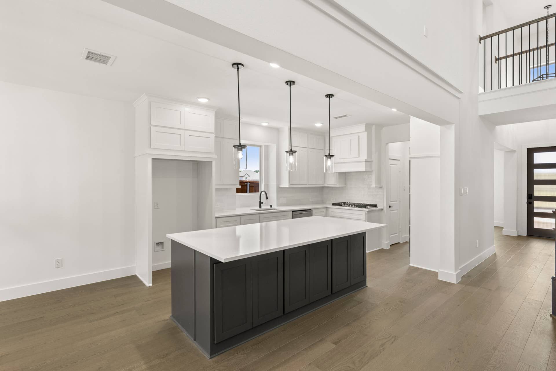Modern kitchen with large island, pendant lighting, and hardwood floors.