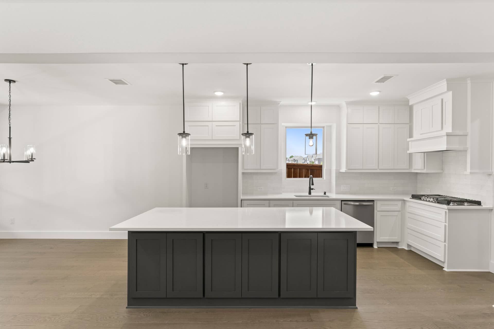 Modern kitchen with white cabinetry, large island, and pendant lighting.