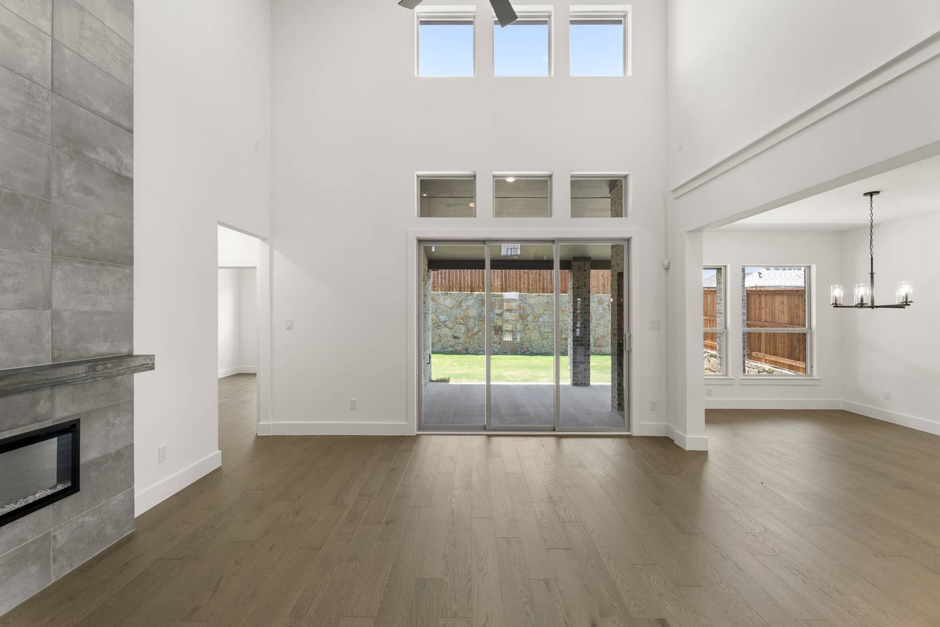 Spacious modern living room with high ceiling and glass doors to patio.