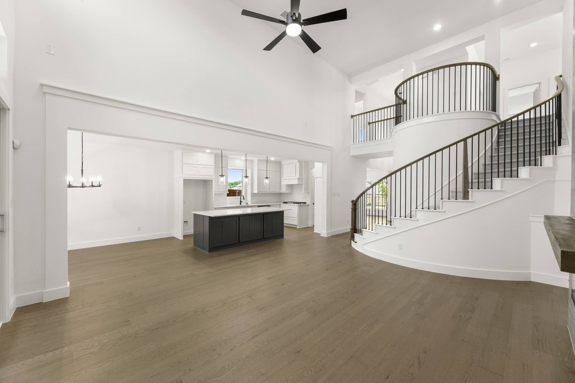 Spacious modern kitchen with island and elegant curved staircase.
