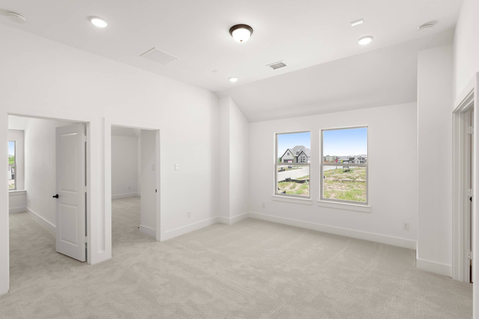 Spacious, bright interior room with neutral carpet and multiple doorways.