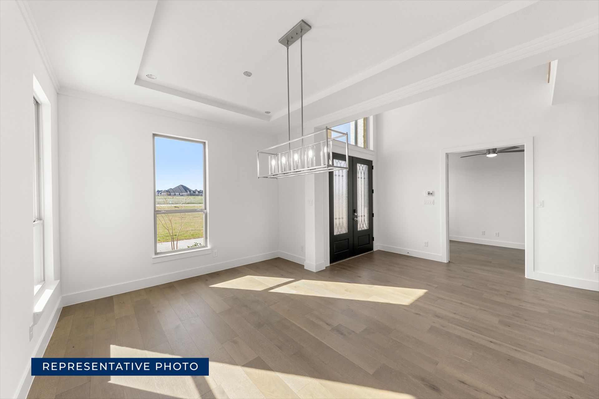 Spacious modern living room with hardwood floors and large windows.
