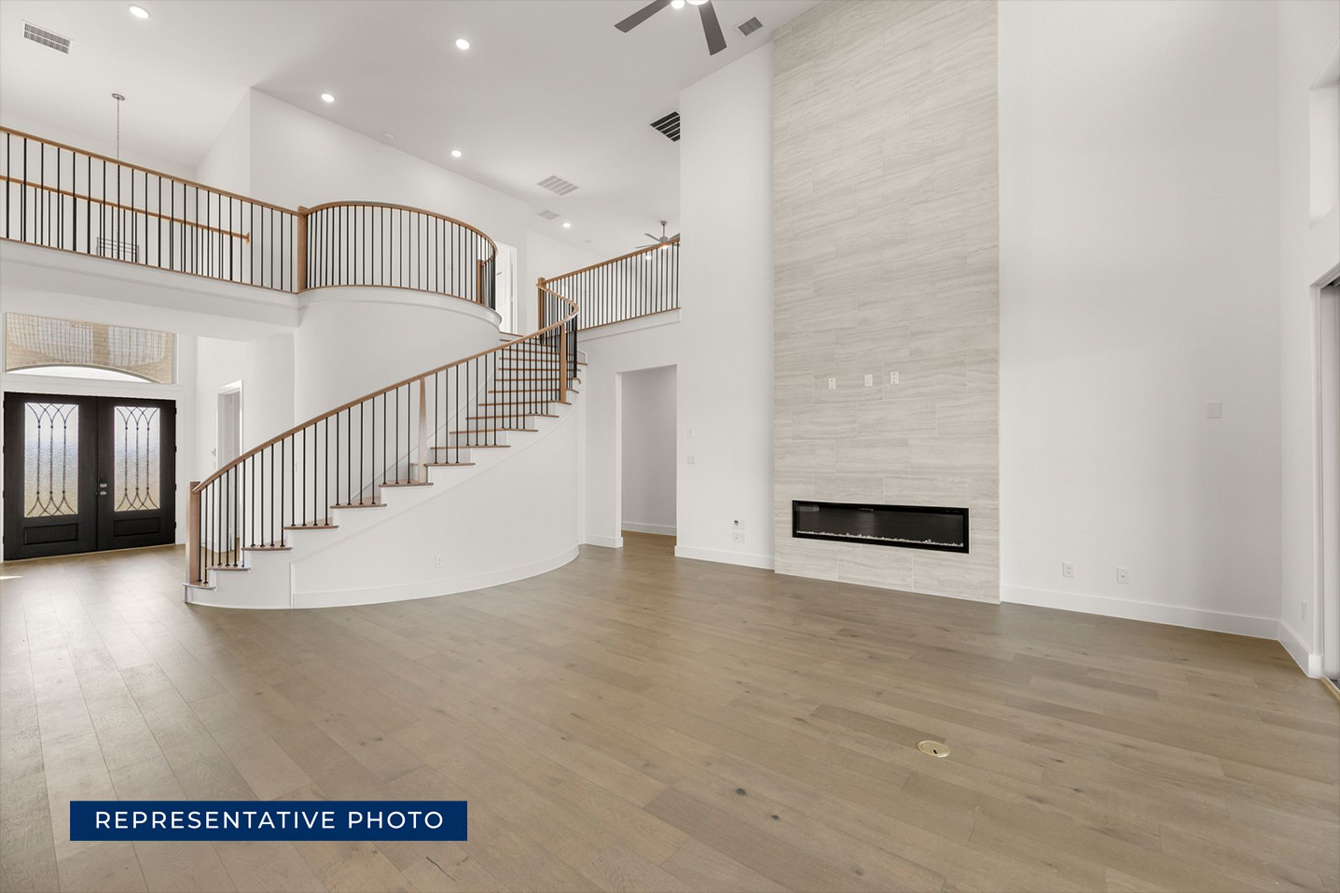 Spacious modern living room with curved staircase and floor-to-ceiling fireplace.