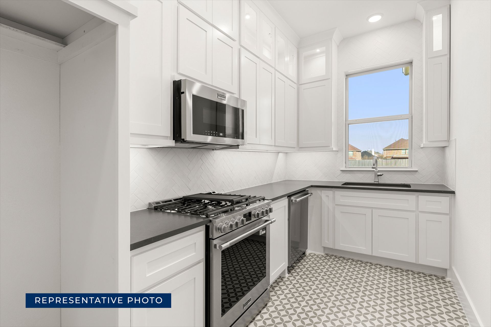 Modern kitchen with white cabinets, stainless steel appliances, and patterned tile floor.