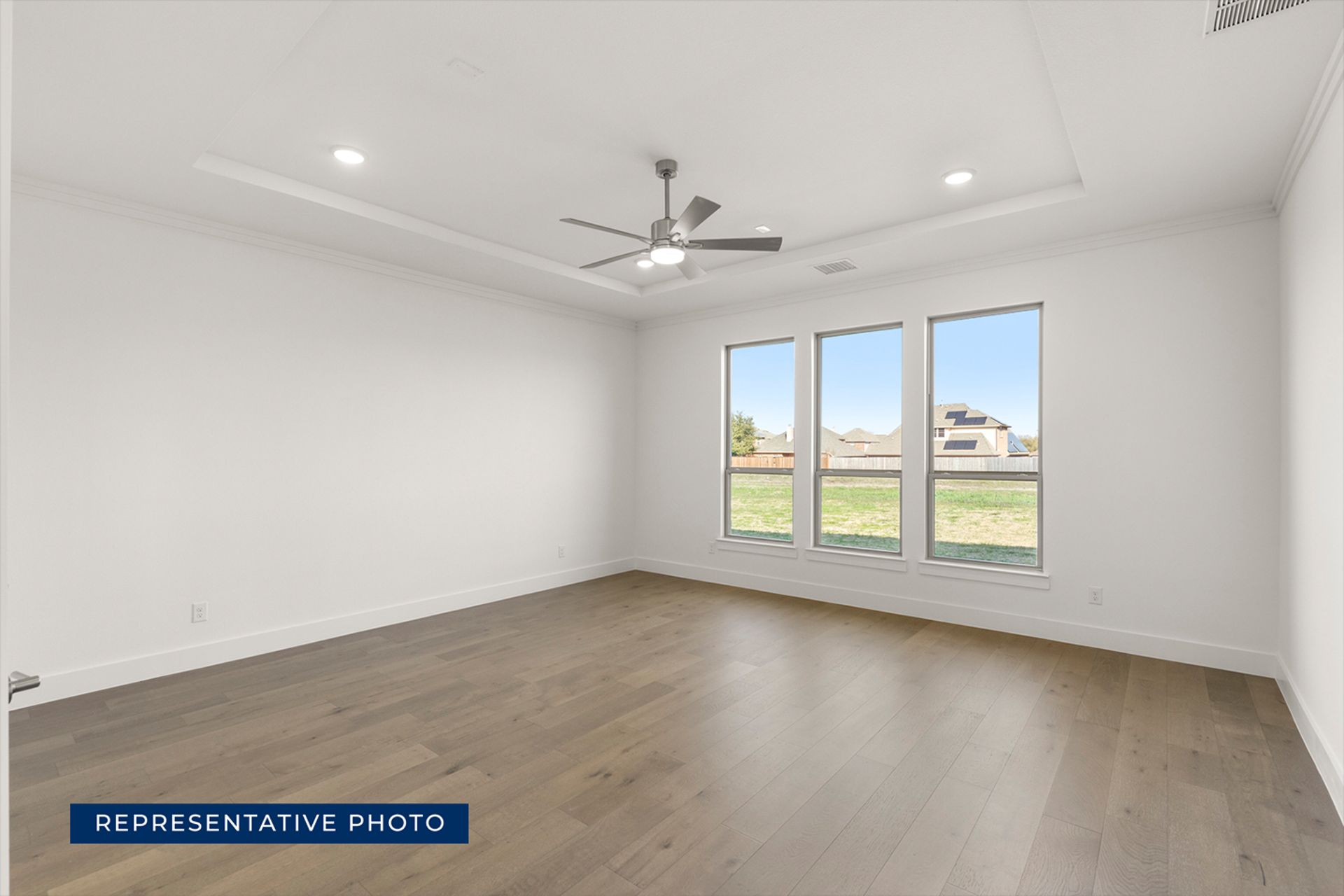 Spacious empty room with large windows and wooden flooring.