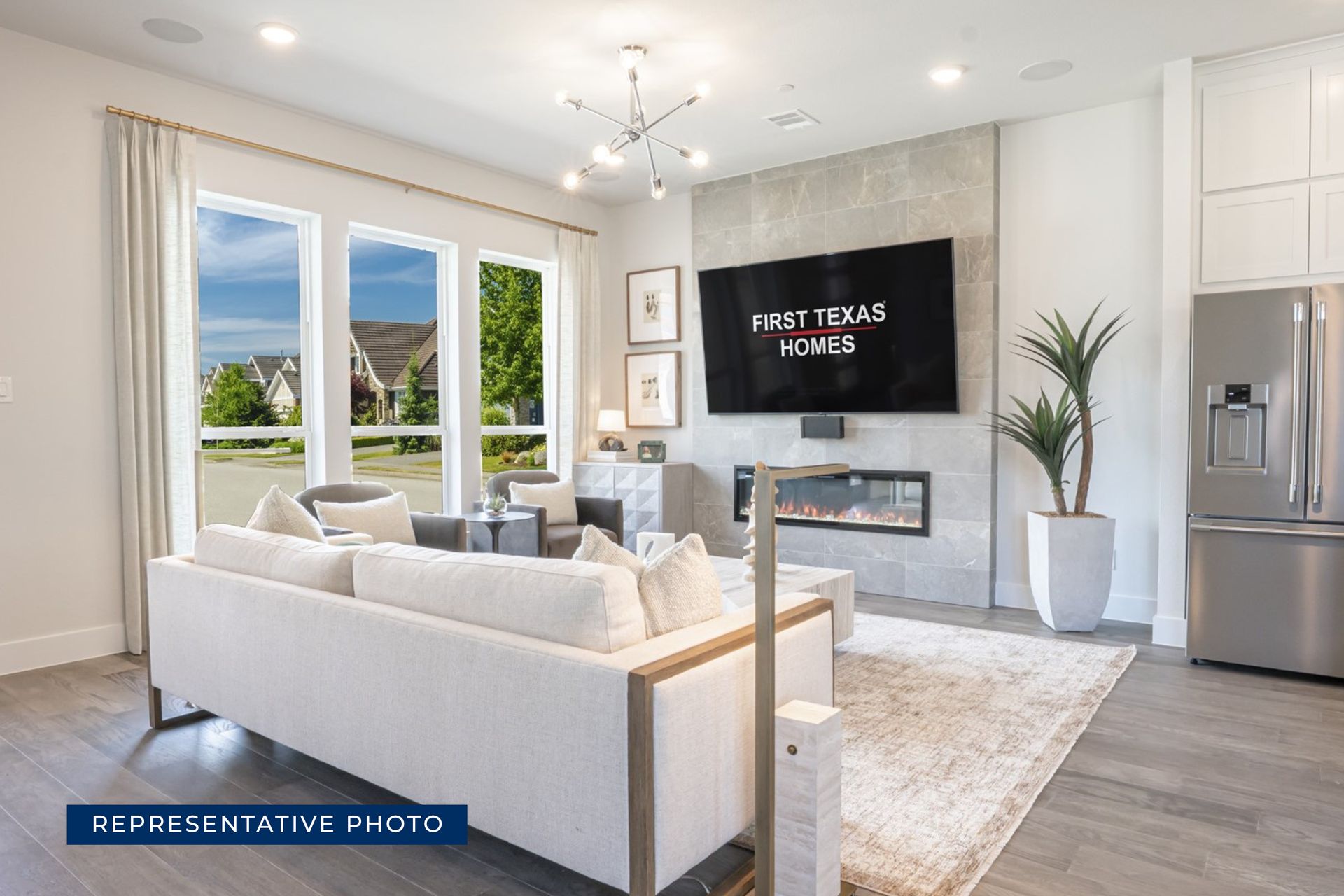Modern living room with fireplace and large windows by First Texas Homes.