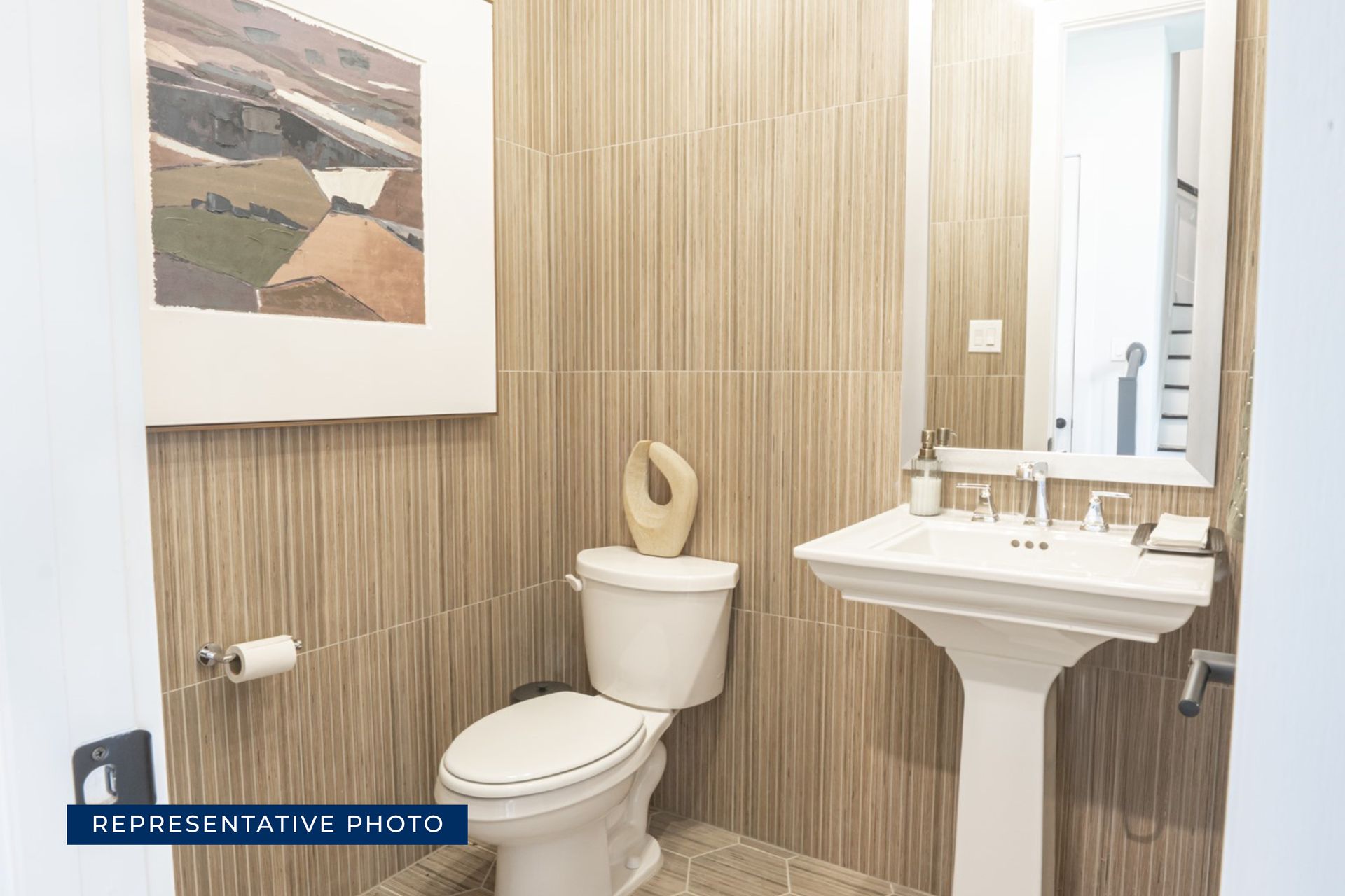 Modern bathroom with pedestal sink, toilet, and wall art.