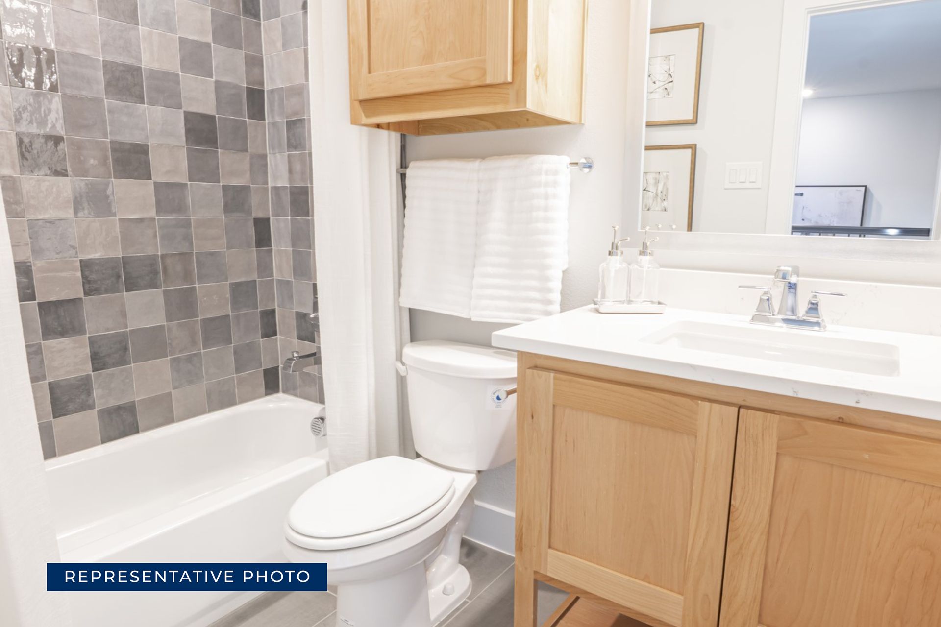 Modern bathroom with wooden vanity, tiled shower, and white fixtures.