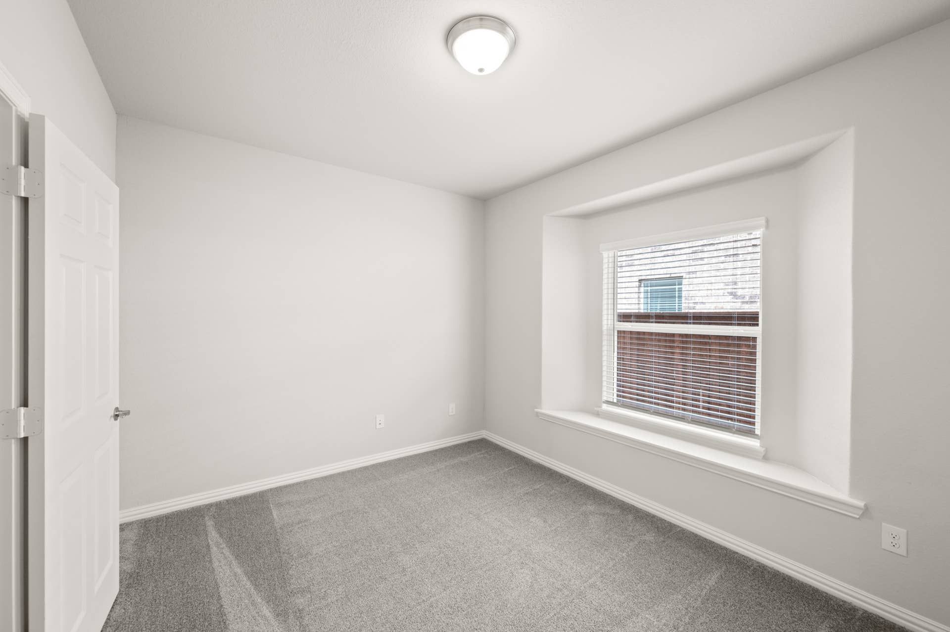 Bright study or bedroom with carpet and large window.