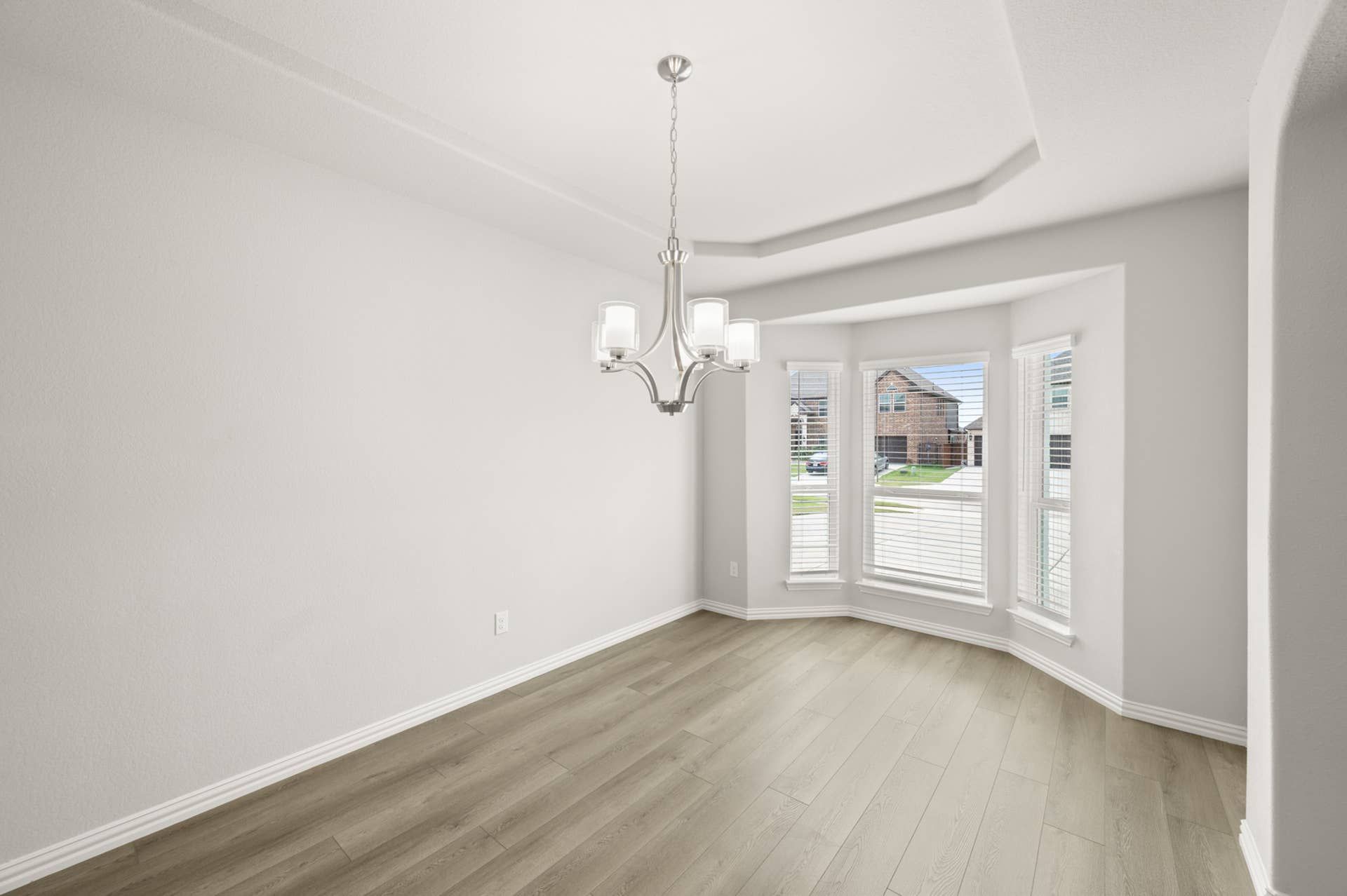 Bright dining room with chandelier and large bay window.