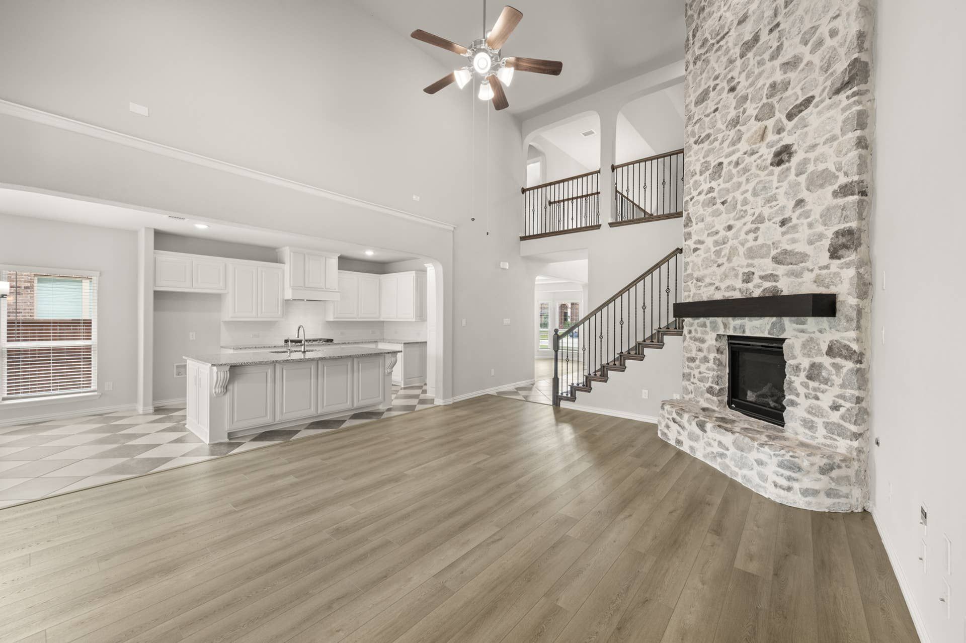 Spacious living room with stone fireplace, open kitchen, and vaulted ceiling.