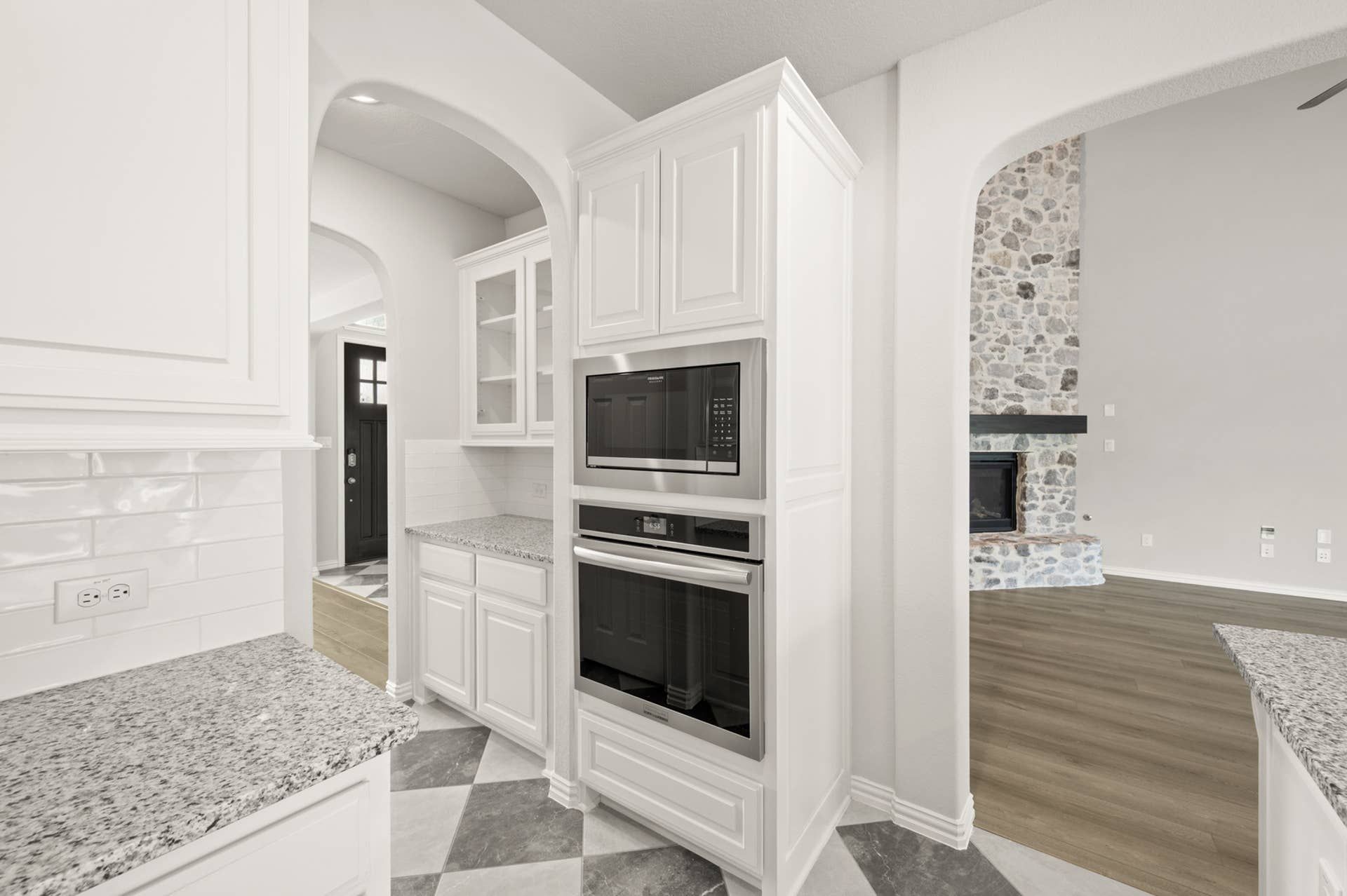 Modern kitchen with white cabinetry, granite countertops, and built-in stainless steel appliances.