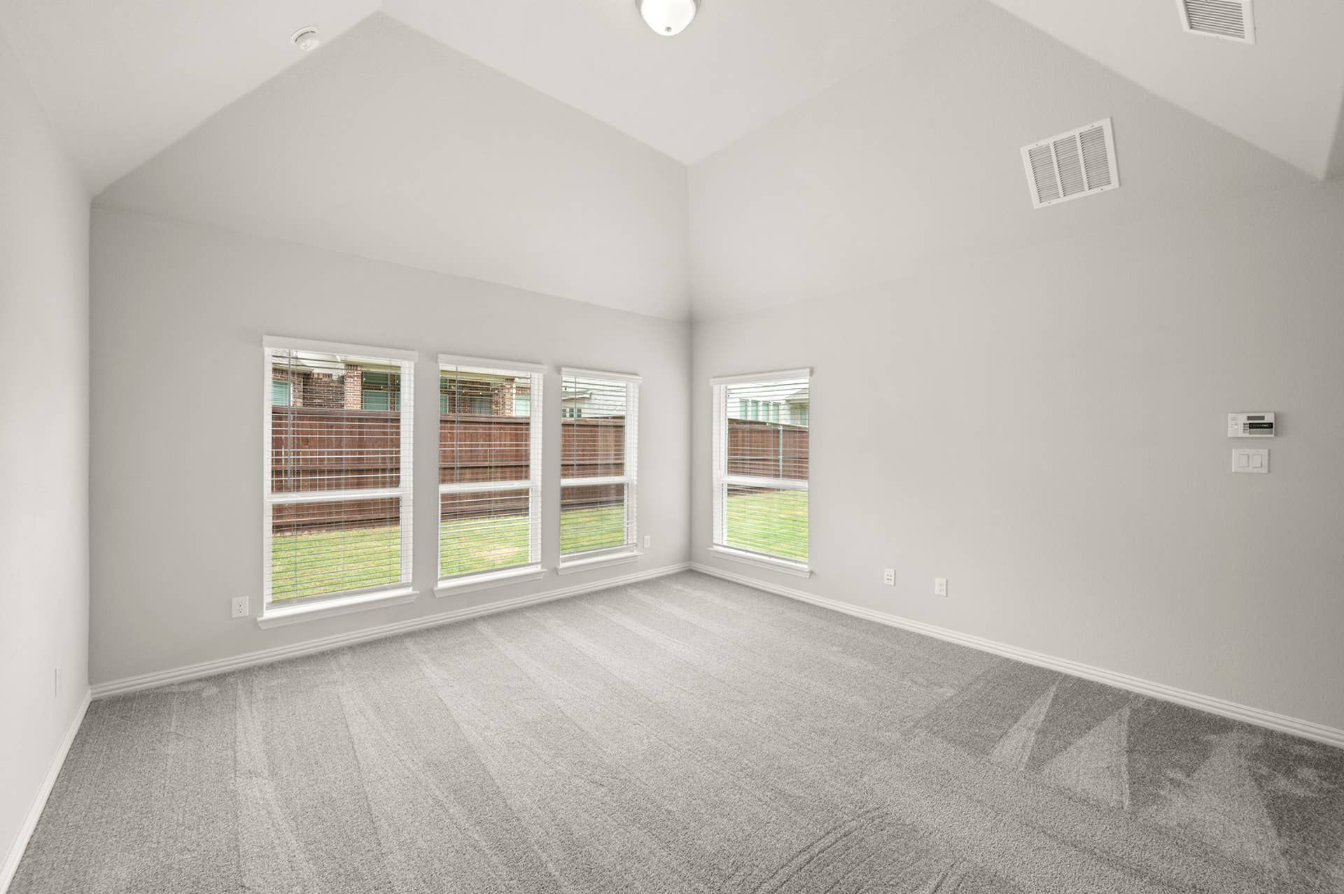Spacious primary suite with large windows and plush carpet flooring.