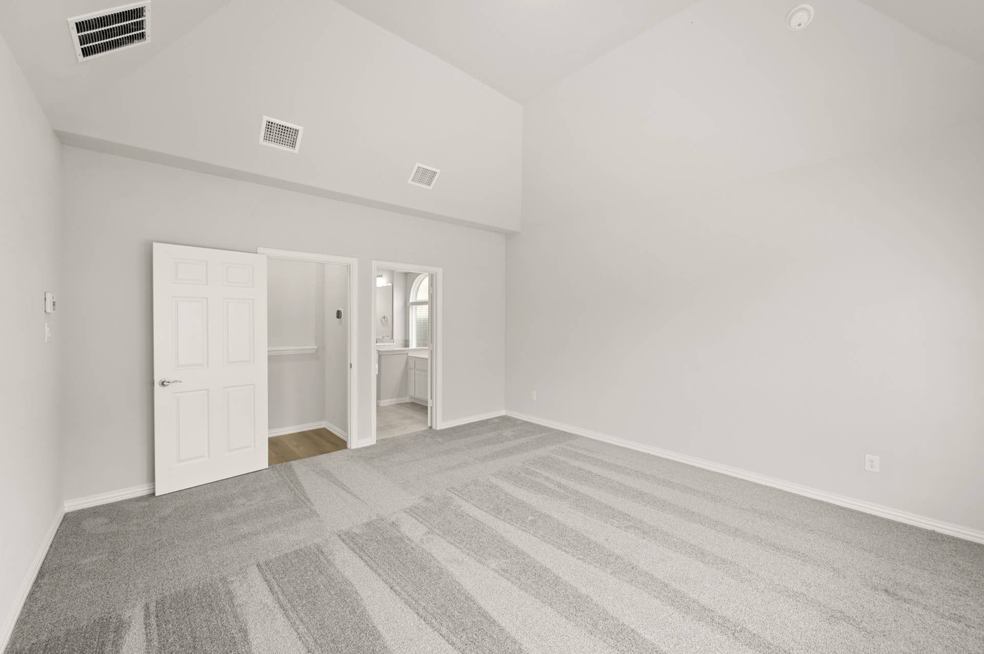 Spacious primary suite with vaulted ceiling and adjacent bathroom entrance.