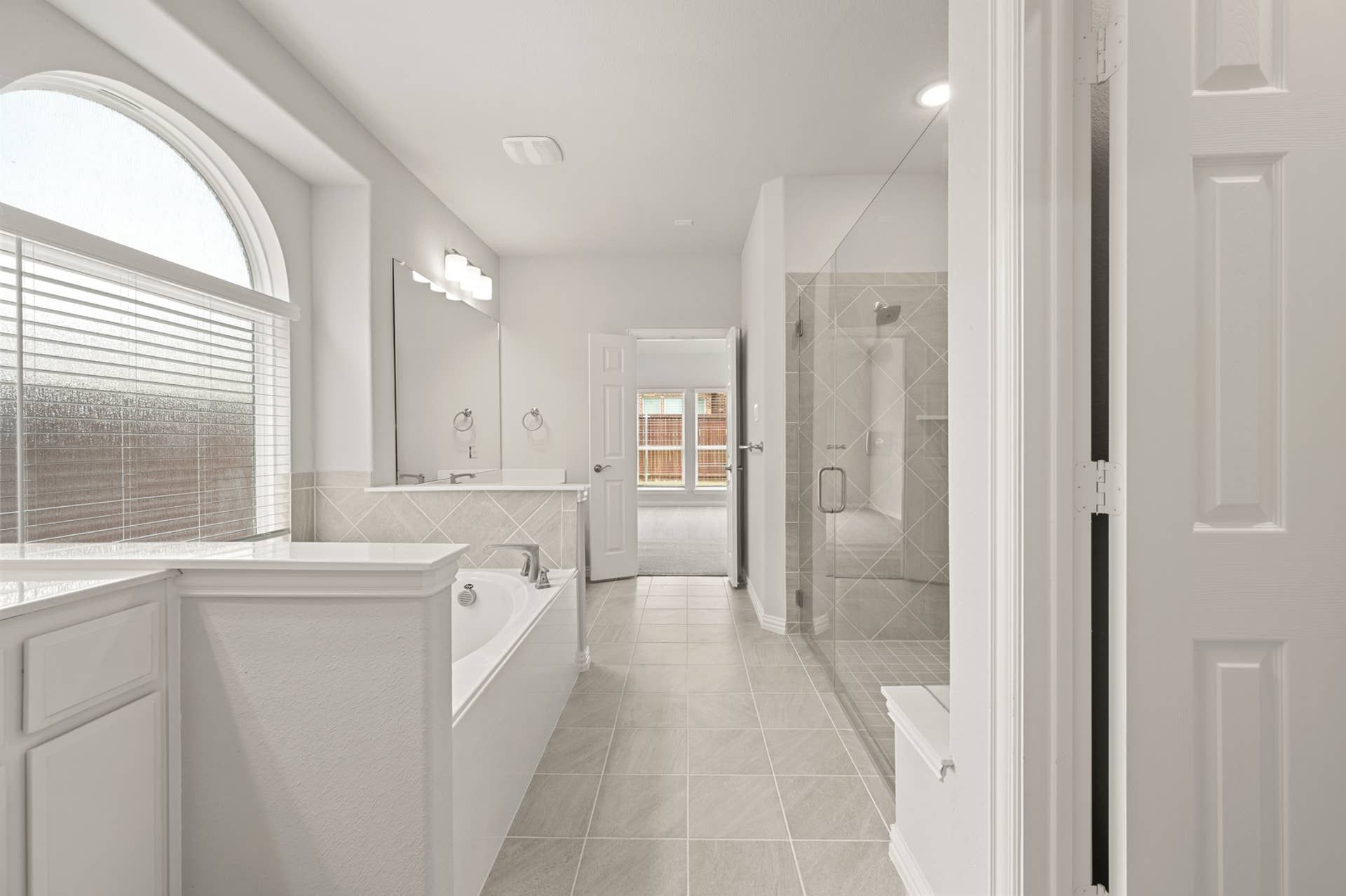 Spacious primary suite bathroom with large tub and glass-enclosed shower.