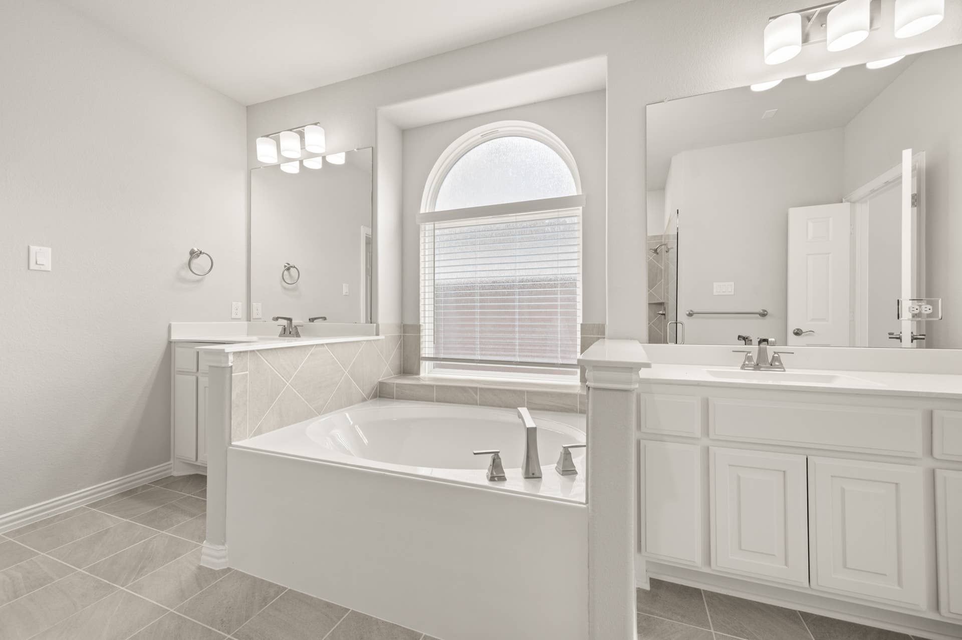 Luxurious primary suite bathroom with soaking tub and dual vanities.