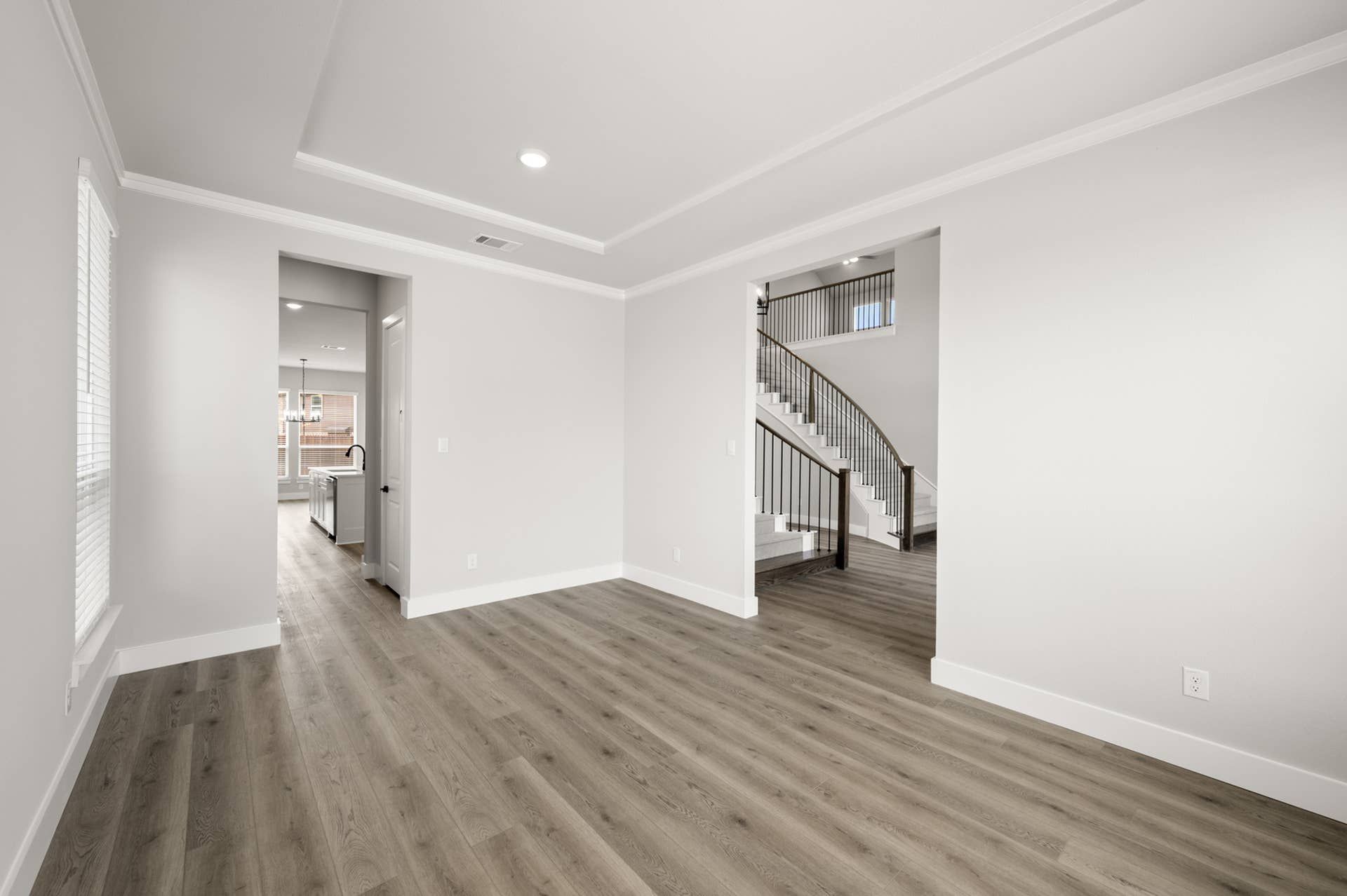 Spacious dining room with hardwood floors and view of elegant staircase.