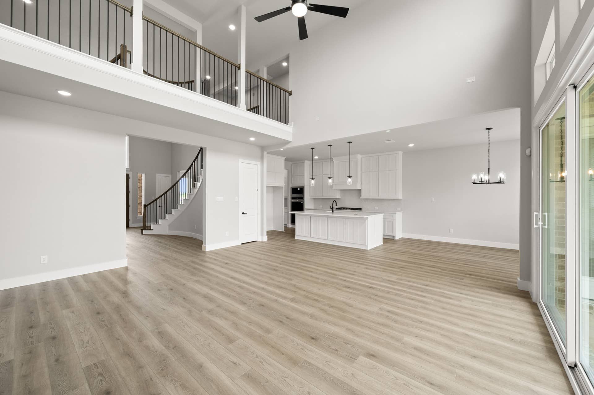 Spacious living room with high ceilings, open layout, and modern kitchen.