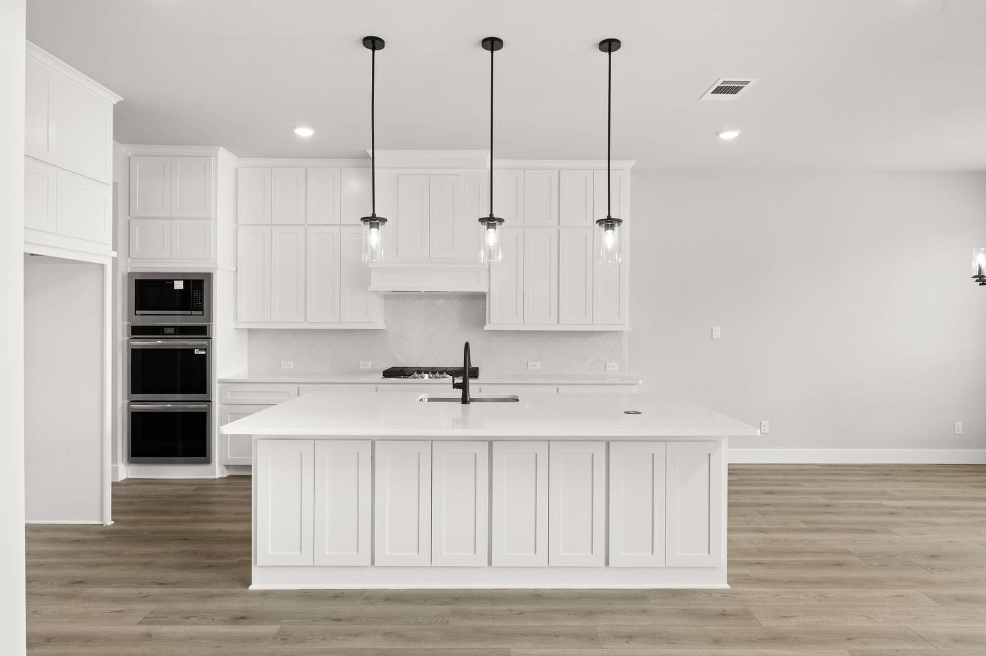 Modern kitchen with white cabinetry, large island, and pendant lighting.