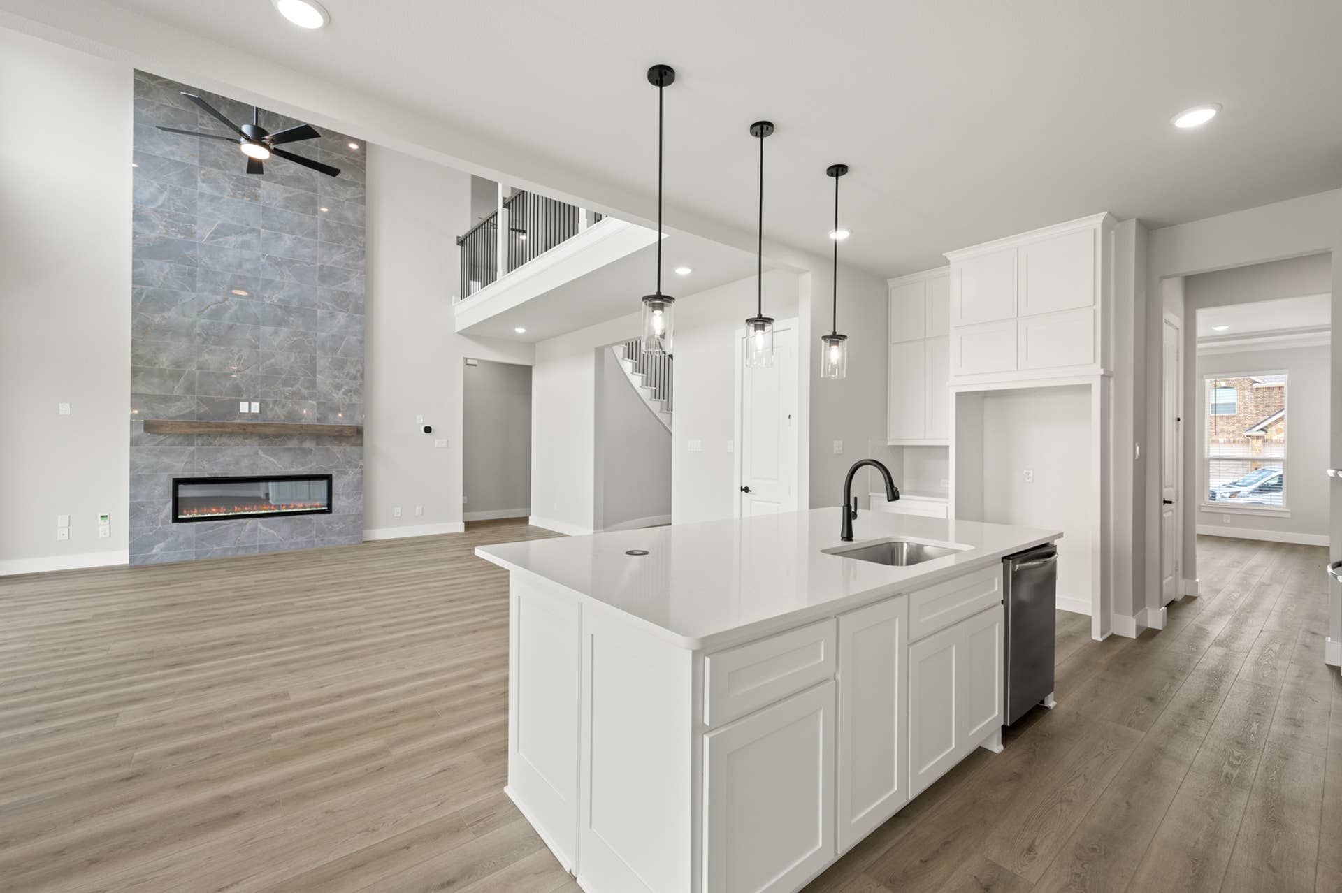Modern kitchen with island, pendant lighting, and open living space with fireplace.