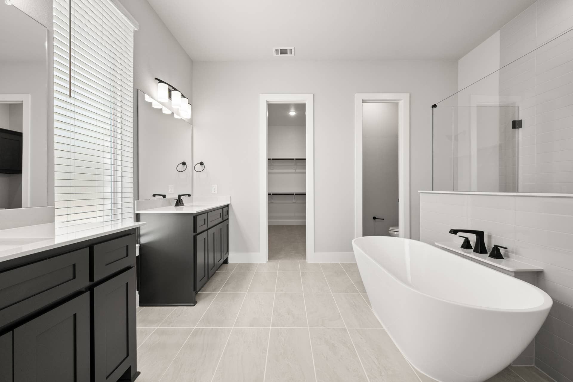 Modern primary suite bathroom with freestanding tub and dual vanities.