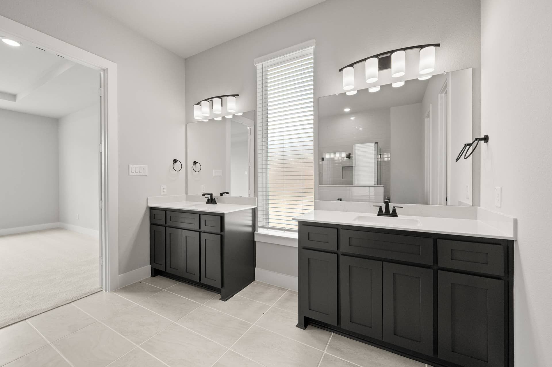 Modern bathroom with dual sinks, dark cabinetry, and bright natural lighting.